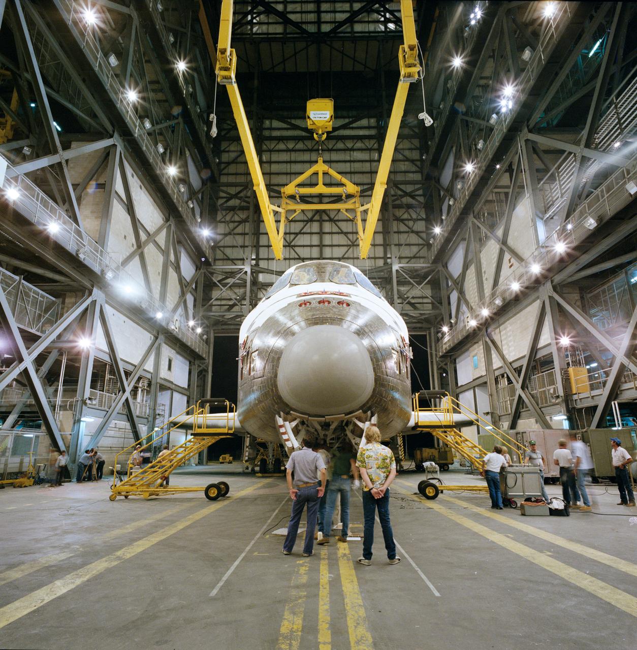 S84-35097 (May 1984) --- The Space Shuttle Orbiter 103 is about to be hoisted into a tail-toward-ground mode for mating to its two solid rocket boosters (SRB) and an external tank (ET) (awaiting the maneuver high out of frame) in the Kennedy Space Center's (KSC) huge vehicle assembly building (VAB).  After its arrival here from the manufacturer in Palmdale, California, Discovery underwent extensive pre-launch preparations in the nearby processing facility (OPF).
