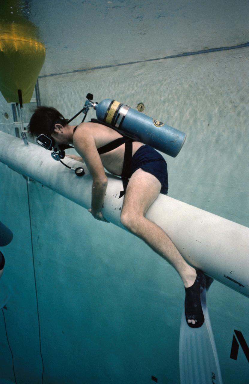 S84-36958 (29 June 1984) --- Astronaut Robert L. Crippen, 41-G crew commander, perches nearby an underwater simulation scene in the Johnson Space Center's weightless environment training facility (WET-F).  Purpose of the rehearsal was to train two of the 41-G crew's mission specialists for a scheduled extravehicular activity (EVA).  Out of frame are Astronauts Kathryn D. Sullivan, Jon A. McBride and David Leestma.  Dr. Sullivan and Leestma donned extravehicular mobility units  (EMU) for the simulation while Crippen and McBride monitored the activity.  This photograph was taken by Otis Imboden.