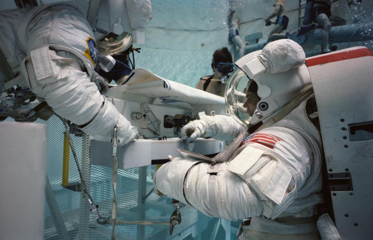 S84-36960 (5 July 1984) --- Astronauts Kathryn D. Sullivan, left, and David C. Leestma, Mission 41-G crewmembers, simulate the transfer of cryogenics in space during an Earth-bound underwater session in the Johnson Space Center's weightless environment training facility (WET-F).  The two mission specialists will be joined by three NASA astronauts and two payload specialists for a flight aboard the Columbia later this year.  The photograph was taken by Otis Imboden.