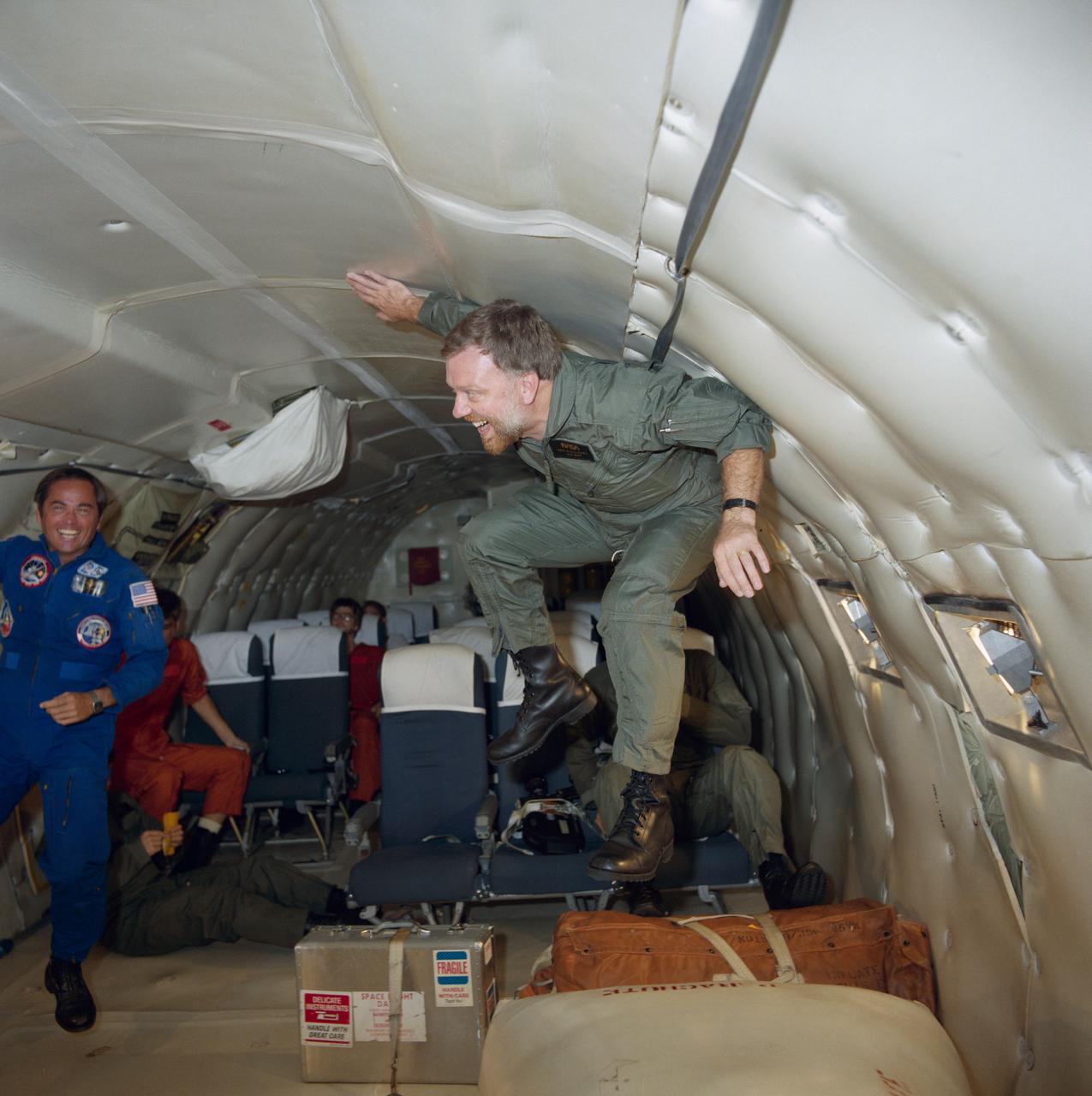 S84-37536 (18 July 1984) --- Astronaut Robert L. Crippen, left, 41-G crew commander watches as one of his fellow crewmembers gets an introduction to weightlessness aboard a KC-135, "zero-gravity" aircraft.  Paul D. Scully-Power is the crew member literally floating here in the brief period of micro-gravity.  Scully-Power, an oceanographer with the U.S. Navy, and Marc Garneau (partially visible in chair behind the floating Scully-Power)are payload specialists for 41-G. Garneau represents the National Research Council   (Canada).