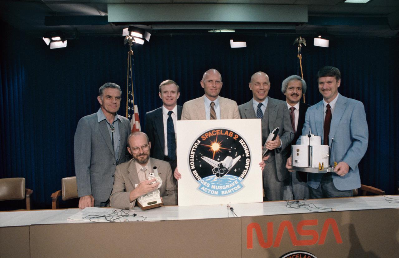 S85-36655 (24 June 1985) --- The seven crewmembers for STS 51-F/Spacelab 2 pose for  photographers following their pre-flight press conference in the Johnson Space Center's public affairs facility.  Standing, l.-r., are Karl J. Henize, mission specialist; Roy D. Bridges, pilot; C. Gordon Fullerton, mission commander; F. Story Musgrave, mission specialist; John-David Bartoe, payload specialist; and Anthony W. England, mission specialist.  Loren W. Acton, payload specialist, is seated.  Launch is scheduled for July of this year.