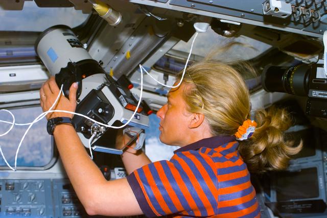 NASA image: Davis holds Large Format camera pointed out the overhead flight deck windows