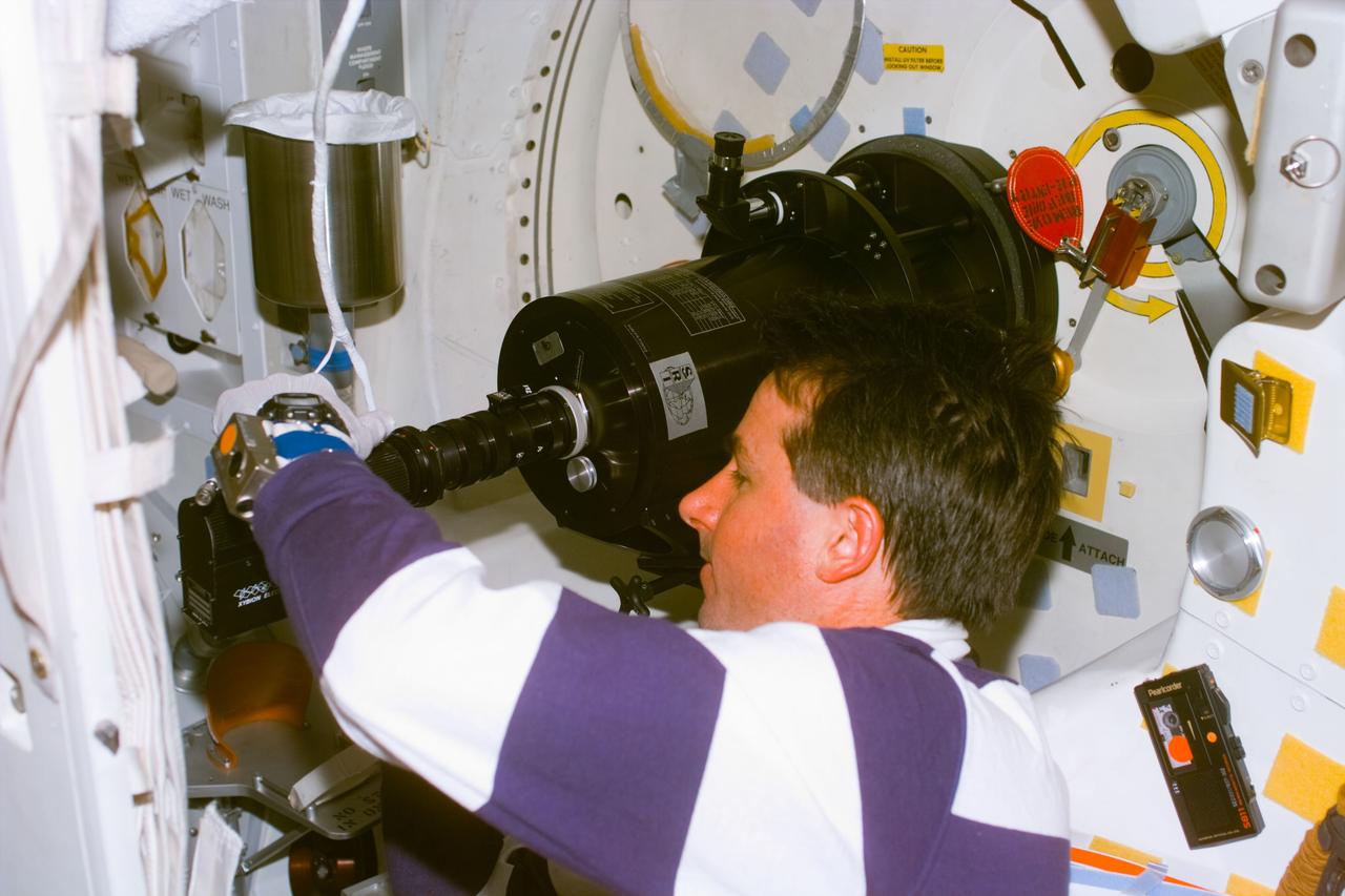 S85-E-5046 (12 August 1997) --- Astronaut Stephen K. Robinson, mission specialist, makes observations with the Southwest Ultraviolet Imaging System (SWUIS) through the Space Shuttle Discovery's hatch window during flight day six.  The photograph was taken with the Electronic Still Camera (ESC).