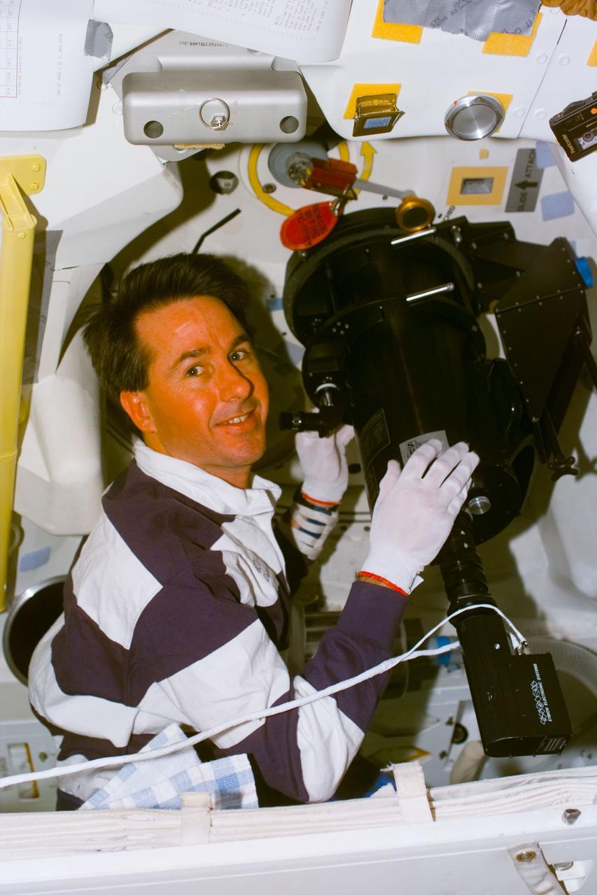 S85-E-5048 (7 - 19 August 1997) --- Astronaut Stephen K. Robinson, mission specialist, performing the Southwest Ultraviolet Imaging System (SWUIS) observations through the Space Shuttle Discovery's hatch window during flight day six.