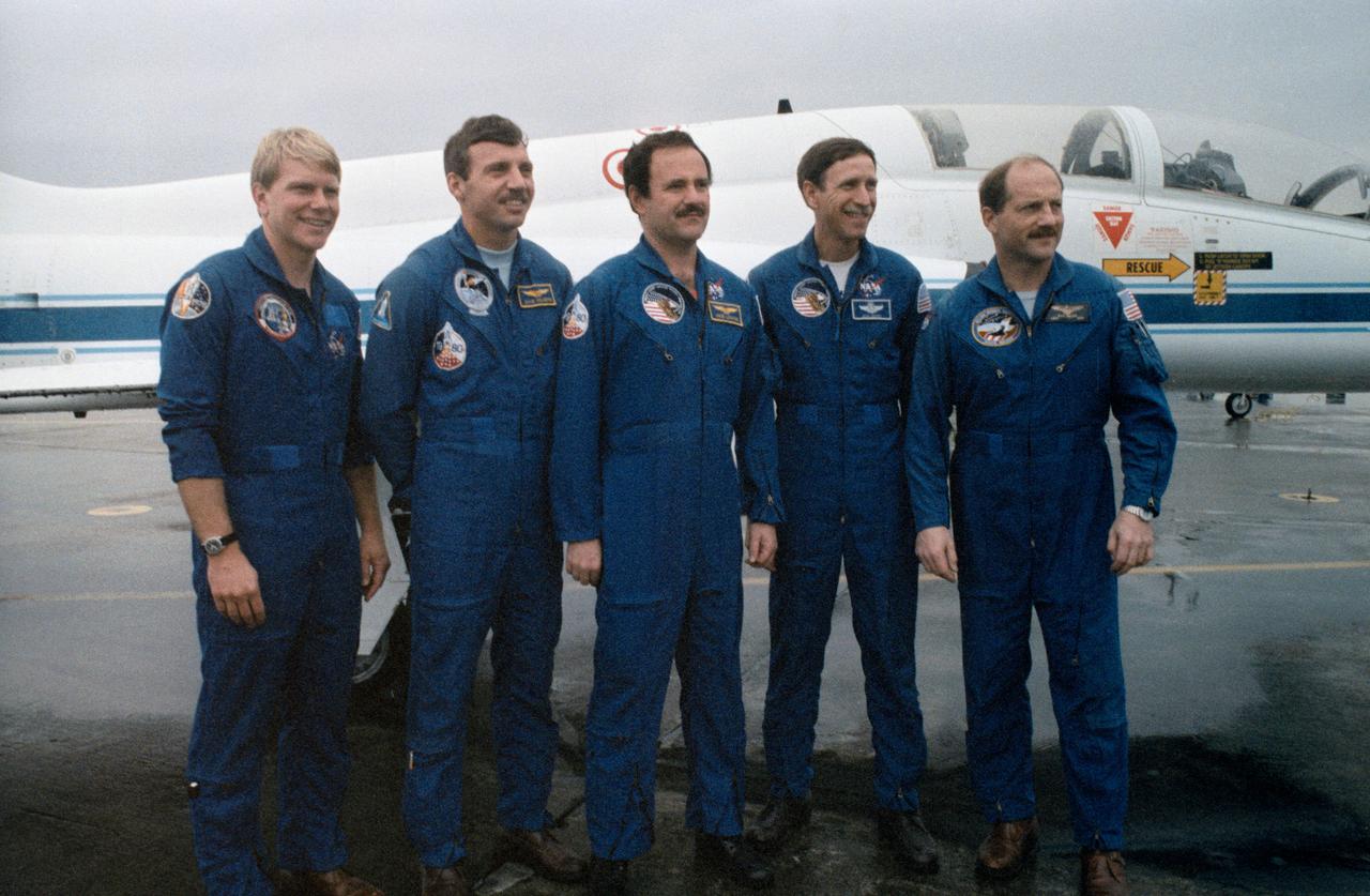 S87-28139 (26 Feb 1987) --- The five veteran astronauts recently assigned to the STS 26 space mission pose for photographers prior to departure from Ellington Field in T-38 jets (parked in background). Astronaut Frederick H. (Rick) Hauck (right) is mission commander. Astronaut Richard O. Covey, second right, is pilot; and (l.-r.) Astronauts George D. Nelson, David C. Hilmers and John M. (Mike) Lounge are mission specialists. The five were headed for KSC in Florida where they were to interface with flight hardware. The Discovery has been assigned as the STS 26 Shuttle vehicle.
