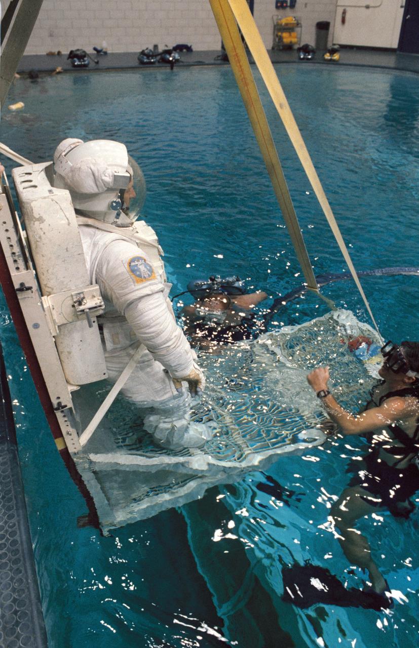 S87-44061 (25 Sept 1987)  ---  Dr. Claude Nicollier, equipped with a pressurized extravehicular mobility unit (EMU), is in the process of being submerged in the 25-ft. deep pool of JSC's weightless environment training facility (WET-F) for a familiarization session.  Dr. Nicollier's suit is weighted to facilitate a neutrally buoyant condition.  He is assisted by two SCUBA-equipped divers.  Dr. Nicollier, a Swiss scientist assigned to the STS-46 mission as a payload specialist, first came to the Johnson Space Center in July 1980. Along with Dr. Wubbo Ockels, another European Scientist, Dr. Nicollier underwent survival training and other basic astronaut-type training alongside the 1980 class of astronaut candidates. Some photos in this series show Dr. Nicollier in an extravehicular mobility unit (EMU).  This is for familiarization purposes only as the scientist is not scheduled for any extravehicular activity.