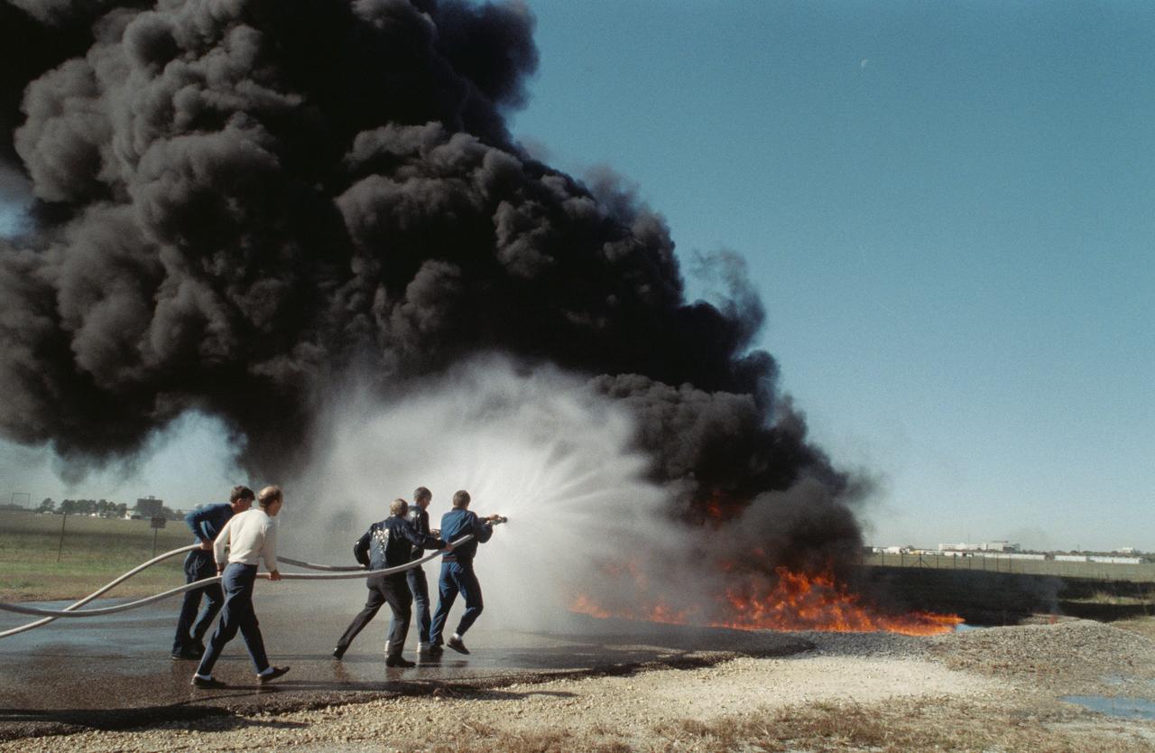 S88-54947 (6 Dec 1988) --- The STS-29 crewmembers are trained in procedures to follow in the event of a fire with their spacecraft.  Here, Astronauts Michael L. Coats (far left), mission commander, and James P. Bagian, mission specialist, follow the lead of two fellow crewmembers as they extinguish a fire. The astronauts in front of the action are Robert C. Springer, mission specialist, and John E. Blaha, pilot.  Not pictured is James F. Buchli, mission specialist. Their instructor, center, is Robert Fife of NASA's security staff. The training took place on the northern end of the 1625-acre JSC facility.