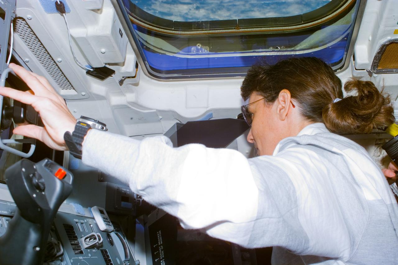 S88-E-5030 (12-05-98) ---     Astronaut Nancy J. Currie gently mated the 12.8-ton Unity connecting module to Endeavour's docking system late afternoon of Dec. 5, successfully completing the first task in assembling the new International Space Station.  Deftly manipulating the shuttle's 50-foot-long robot arm, Currie placed Unity just inches above the extended outer ring on Endeavour's docking mechanism, enabling astronaut Robert D. Cabana, mission commander, to fire downward maneuvering jets, locking the shuttle's docking system to one of two Pressurized Mating Adapters (PMA) attached to Unity. Turning her head to her right, Currie is using one of the TV monitors on the aft flight deck to assist in the precise maneuver. The photo was taken with an electronic still camera (ESC) at 22:31:08 GMT, Dec. 5.
