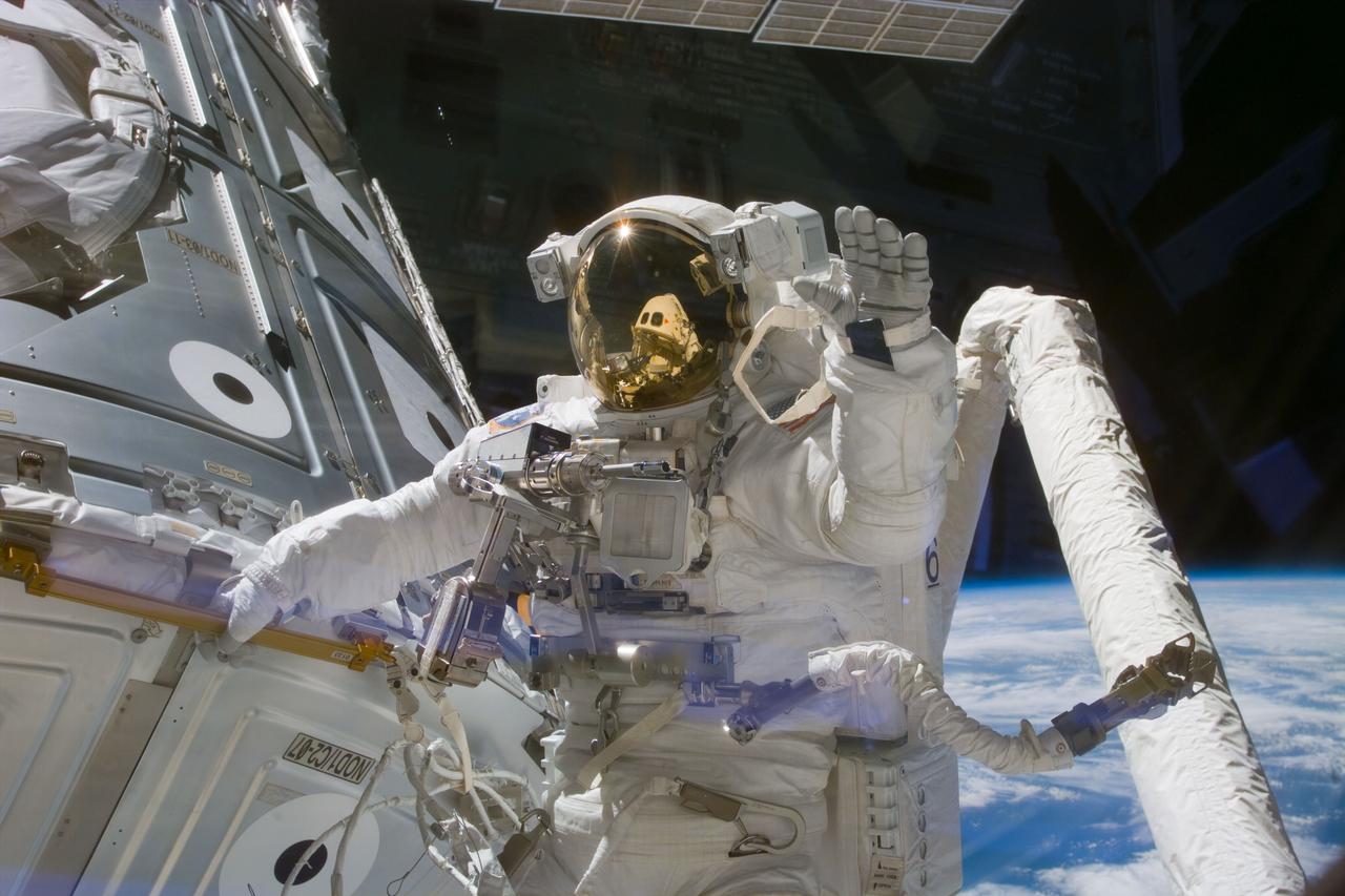 S88-E-5057 (12-07-98) --- Astronaut James H. Newman, waves at camera as he holds onto one of the hand rails on the Unity connecting module during the early stages of a 7-hour, 21-minute spacewalk. Astronauts Newman and Jerry L. Ross, both mission specialists, went on to mate 40 cables and connectors running 76 feet from the Zarya control module to Unity, with the 35-ton complex towering over Endeavour's cargo bay. This photo was taken with an electronic still camera (ESC) at 23:37:40 GMT, Dec. 7.