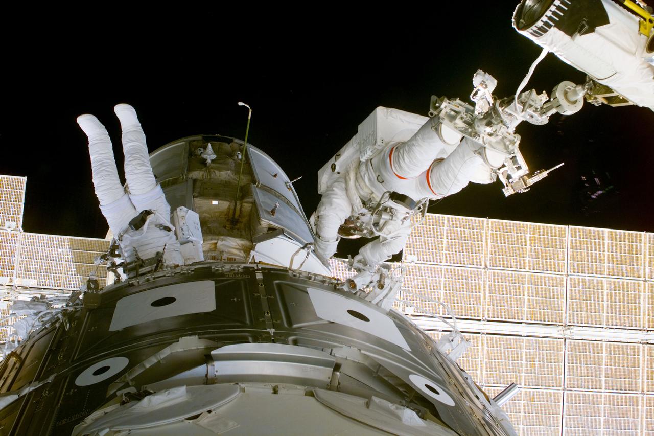S88-E-5059 (12-08-98) --- Astronauts  James H. Newman (left) and Jerry L. Ross  work between Zarya and Unity (foreground) during the first of three scheduled spacewalks on the STS-88 mission.  Newman is tethered to the module, while Ross is anchored at the feet to a mobile foot restraint mounted on the end of the remote manipulator system (RMS) arm.
