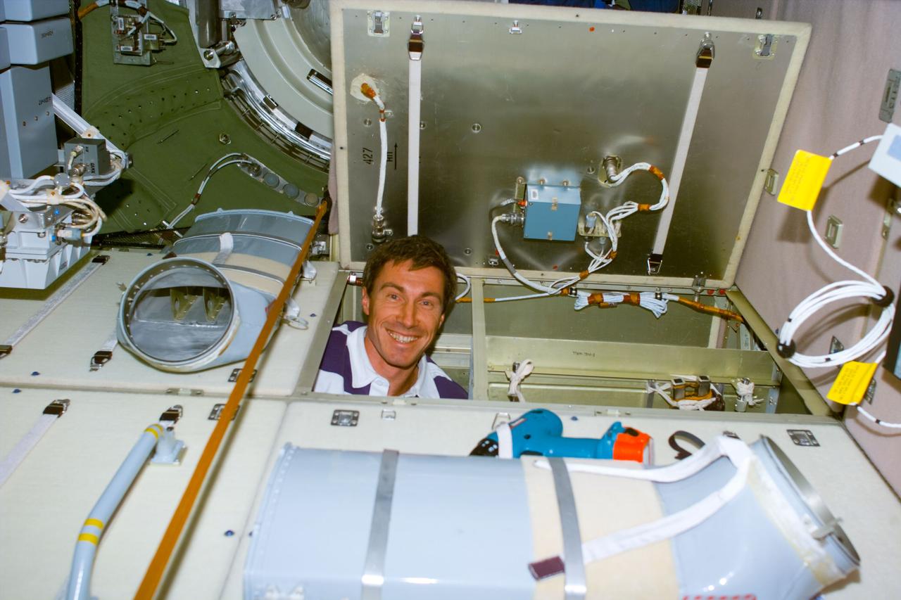 S88-E-5086 (12-11-98) --- Sergei Krikalev, mission specialist representing the Russian Space Agency (RSA), pokes his head up from inside one of the bays inside the walls on the Russian-built Zarya module. Krikalev and astronaut Nancy J. Currie replaced a faulty unit which controls the discharging of stored energy from one of Zarya's six batteries.  The photo was taken with an electronic still  camera (ESC) at 05:41:18 GMT, Dec. 11.