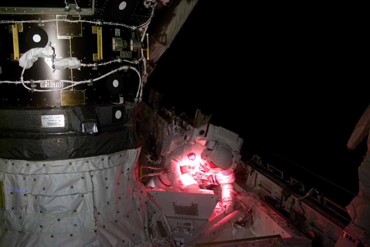 S88-E-5104 (12-10-98) With the Shuttle in a "night side" position, astronaut Jerry L. Ross, mission specialist, uses artificial light during the second STS-88 space walk. Ross is near a pressurized module adapter (PMA) on Endeavour's port side. The photo was taken with an electronic still camera (ESC) at 03:10:00 GMT, Dec.  10.