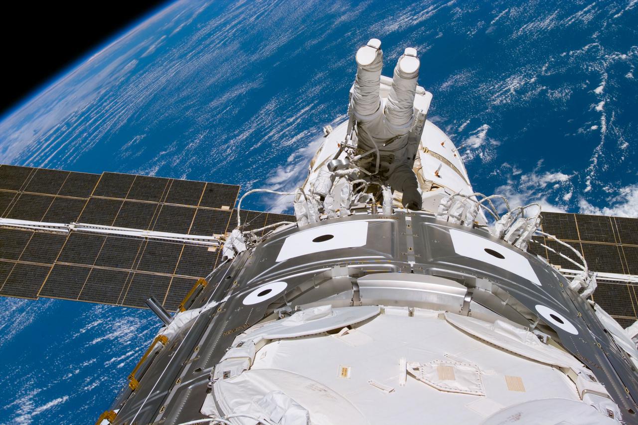 S88-E-5144 (12-12-98) --- Astronaut James H. Newman, mission specialist, wraps up extravehicular activity (EVA) tasks as he and fellow mission specialist Jerry L. Ross (out of frame) approach the completion of their third and final scheduled space walk on STS-88. Newman holds onto handrails on the U.S.-built Unity connecting module (foreground).  Zarya can be seen beyond Newman, backdropped over ocean waters some 173 nautical miles below.  The photo was taken with an electronic still camera (ESC) at 21:59:39 GMT, Dec. 12.