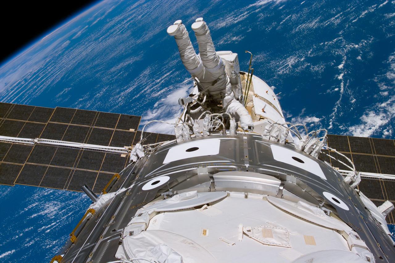 S88-E-5145 (12-12-98) --- Astronaut James H. Newman, mission specialist, wraps up extravehicular activity (EVA) tasks as he and fellow mission specialist Jerry L. Ross (out of frame) near the completion of their third and final scheduled space walk on STS-88.  Newman holds onto handrails on the U.S.-built Unity connecting module (foreground).  Zarya can be seen beyond Newman, backdropped over ocean waters some 173 nautical miles below.  The photo was taken with an electronic still camera (ESC) at 21:59:43 GMT, Dec. 12.