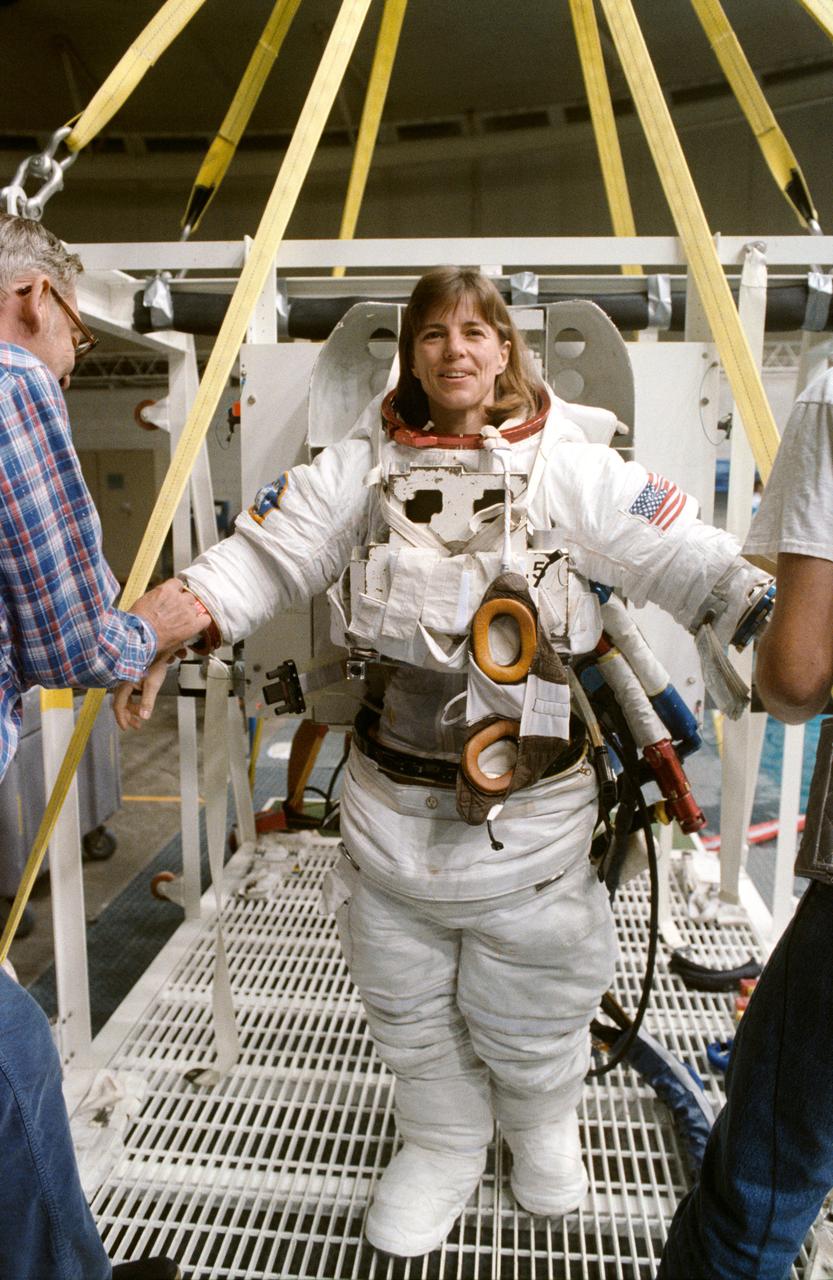S89-41597 (Nov 1989) --- Astronaut Bonnie J. Dunbar, wearing an extravehicular mobility unit (EMU) spacesuit, prepares to don gloves and subsequently a helmet and to be lowered by a hoist device for a session of underwater training in the Johnson Space Center's weightless environment training facility (WET-F).  Minutes later, Astronauts Dunbar and G. David Low, mission specialists, were neutrally buoyant in the nearby 25-ft. deep pool simulating a contingency extravehicular activity (EVA) for the scheduled December 1989 STS-32 mission.  There are no scheduled EVAs for the crew, whose main missions are to retrieve the Long Duration Exposure Facility (LDEF) and to deploy a Syncom satellite.