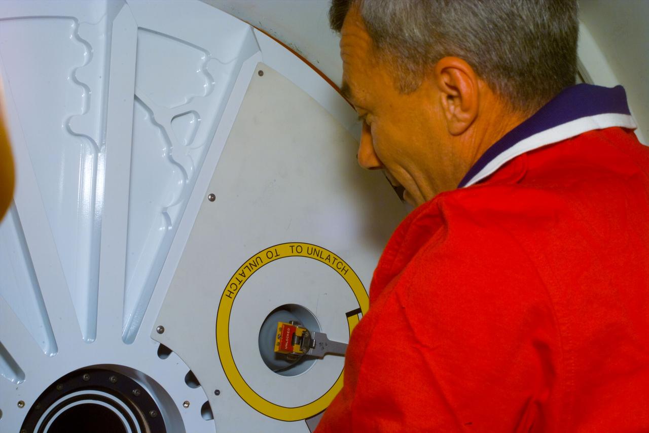 S89-E-5169 (24 Jan 1998) --- Astronaut Terrence W. Wilcutt, mission commander, prepares to open the hatchway to the tunnel that will eventuate an eighth reunion between Shuttle-delivered astronauts and Mir-based cosmonauts in Earth-orbit. The picture was taken with an Electronic Still Camera (ESC) at 22:35:42 GMT, January 24, 1998.
