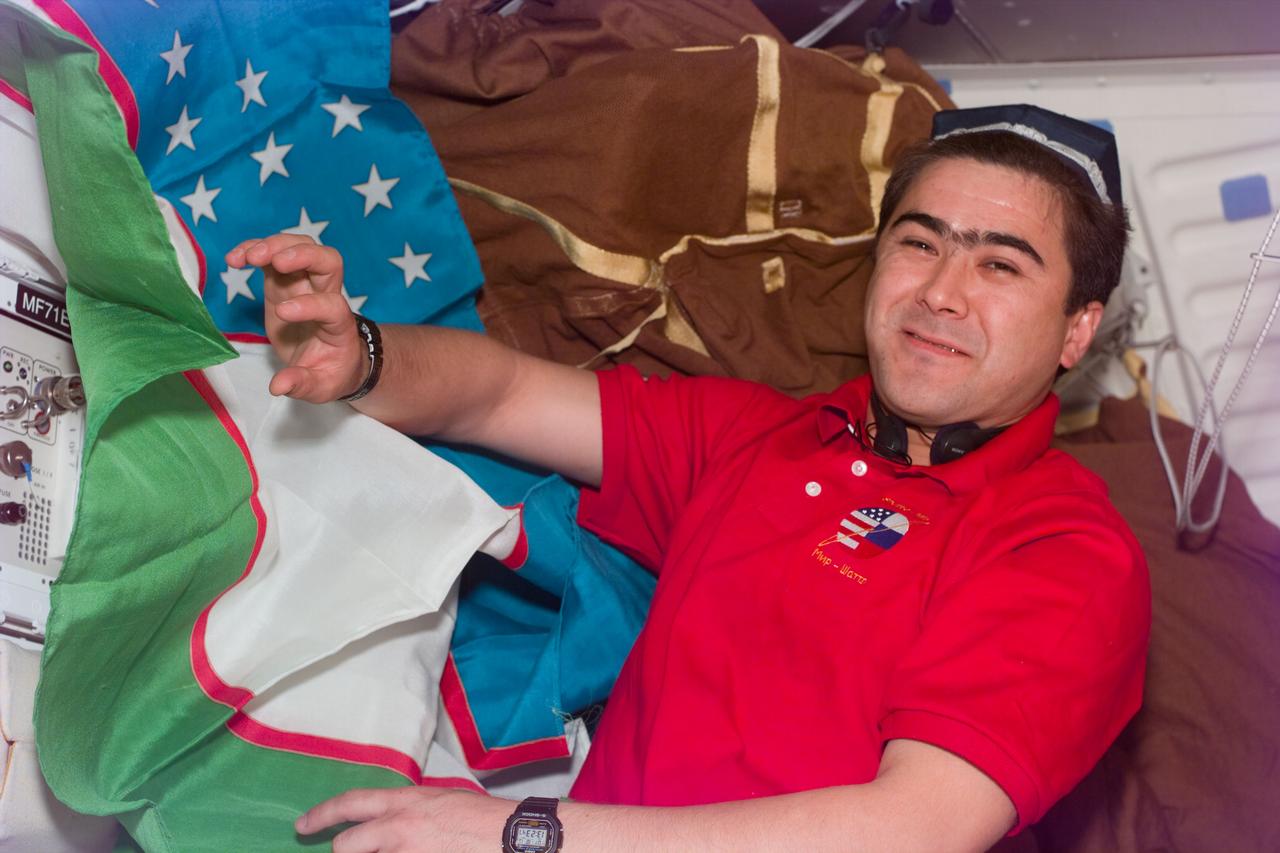 S89-E-5243 (26 Jan 1998) --- This Electronic Still Camera (ESC) image shows cosmonaut Salizan S. Sharipov, payload specialist - representing the Russian Space Agency (RSA), hanging a flag up onboard the Earth-orbiting Space Shuttle Endeavour. This ESC view was taken on January 26, 1998, at 13:23:11 MET.