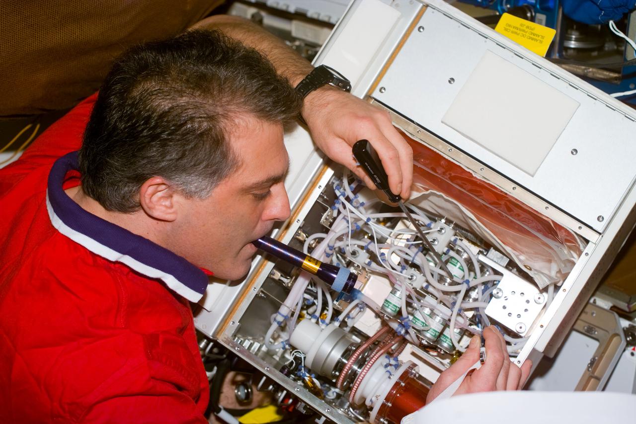 S89-E-5274 (26 Jan 1998) --- This Electronic Still Camera (ESC) image shows astronaut David A. Wolf, mission specialist and cosmonaut guest researcher, holding a pen light in his teeth to get better lighting in this piece of equipment, he is working on onboard the Space Shuttle Endeavour. Wolf is being replaced by astronaut Andrew S. W. Thomas as the cosmonaut guest researcher onboard Russia's Mir Space Station. Thomas will be the last American astronaut to serve onboard the Mir. This ESC view was taken on January 26, 1998, at 14:28:06 GMT.