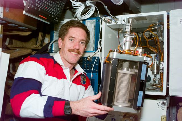 NASA image: MGM - MS Reilly holds a container used in the MGM experiment