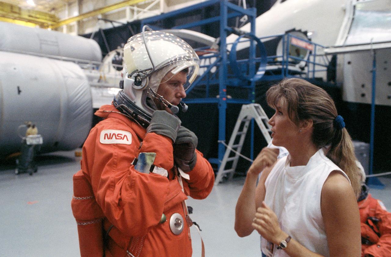 S90-41366 (11 June 1990) --- Astronaut Bryan D. O'Connor, STS-40 mission commander, talks with Elizabeth Youmans of the crew training staff at JSC, during a break in mission training.  This exercise, in JSC's Shuttle mockup and integration laboratory, was designed to familiarize the astronauts with proper procedures and gear involved in emergency egress from the Space Shuttle.  O'Connor is wearing the orange partial pressure ascent/entry suit. Primary payload of the STS-40 mission is Spacelab Life Sciences (SLS-1).