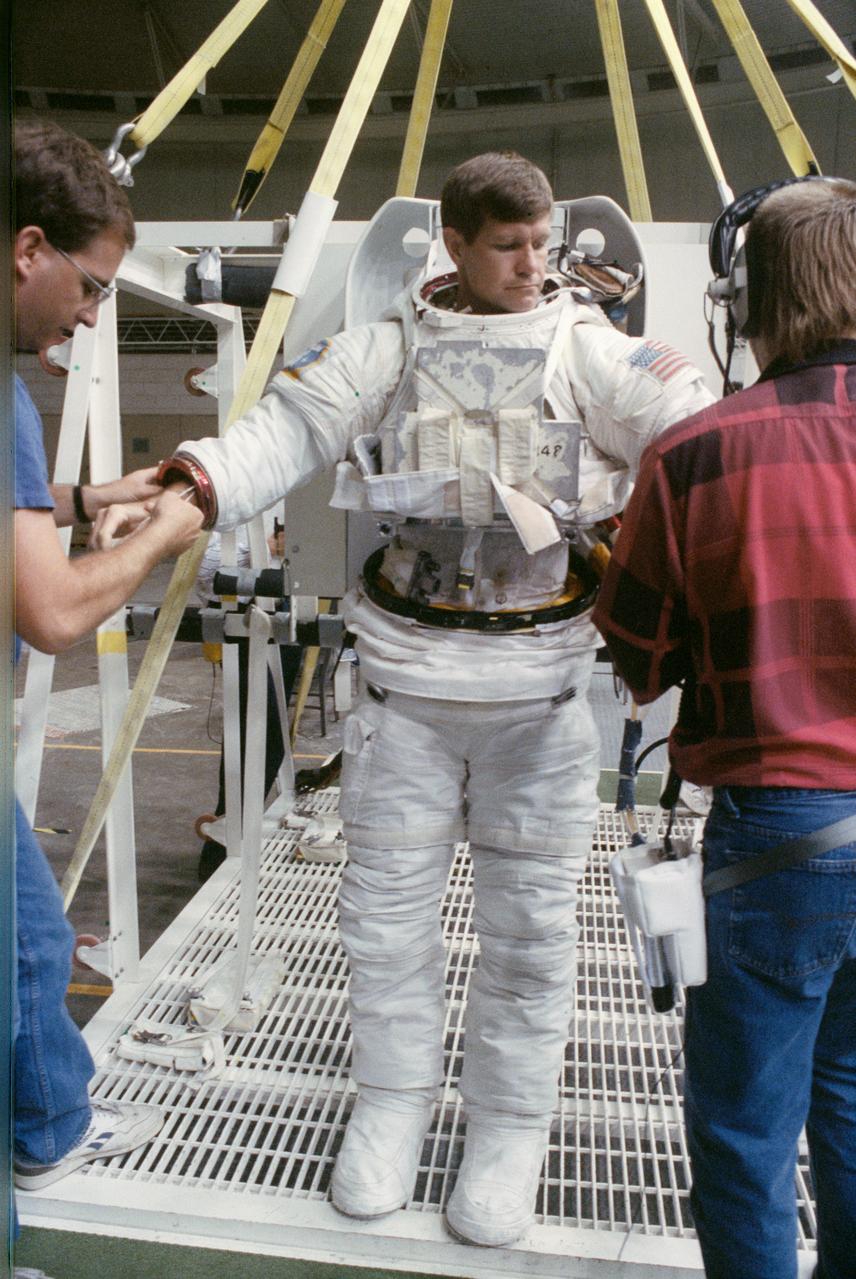 S90-41498 (Aug 1990) --- Astronaut Donald R. McMonagle is about to don gloves for his extravehicular mobility unit (EMU) spacesuit as he prepares to be lowered into a 25-ft. deep pool at the Johnson Space Center's (JSC)weightless environment training facility (WET-F).  McMonagle was preparing to participate in the simulation of a contingency extravehicular activity (EVA) for the mission, scheduled for Discovery in the spring of 1991.