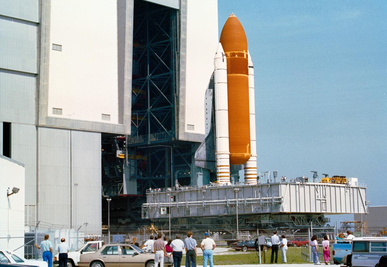 S90-42289 ( 3 July 1990) --- Kennedy Space Center (KSC) workers watch as Columbia, Orbiter Vehicle (OV) 102, along with its external tank (ET) and two solid rocket boosters (SRBs) atop the giant crawler transporter, rolls back to KSC's Vehicle Assembly Building (VAB). The rollback was caused by a hydrogen leak that stopped the STS-35 countdown during ET fueling, 05-29-90. Once in the VAB, OV-102 and its stack will be demated, and OV-102, with its Astronomy Laboratory 1 (ASTRO-1) payload aboard, will be moved to the Orbiter Processing Facility (OPF) to await return to KSC Launch Complex (LC) Pad 39A. View provided by KSC with alternate number KSC-90PC-901.