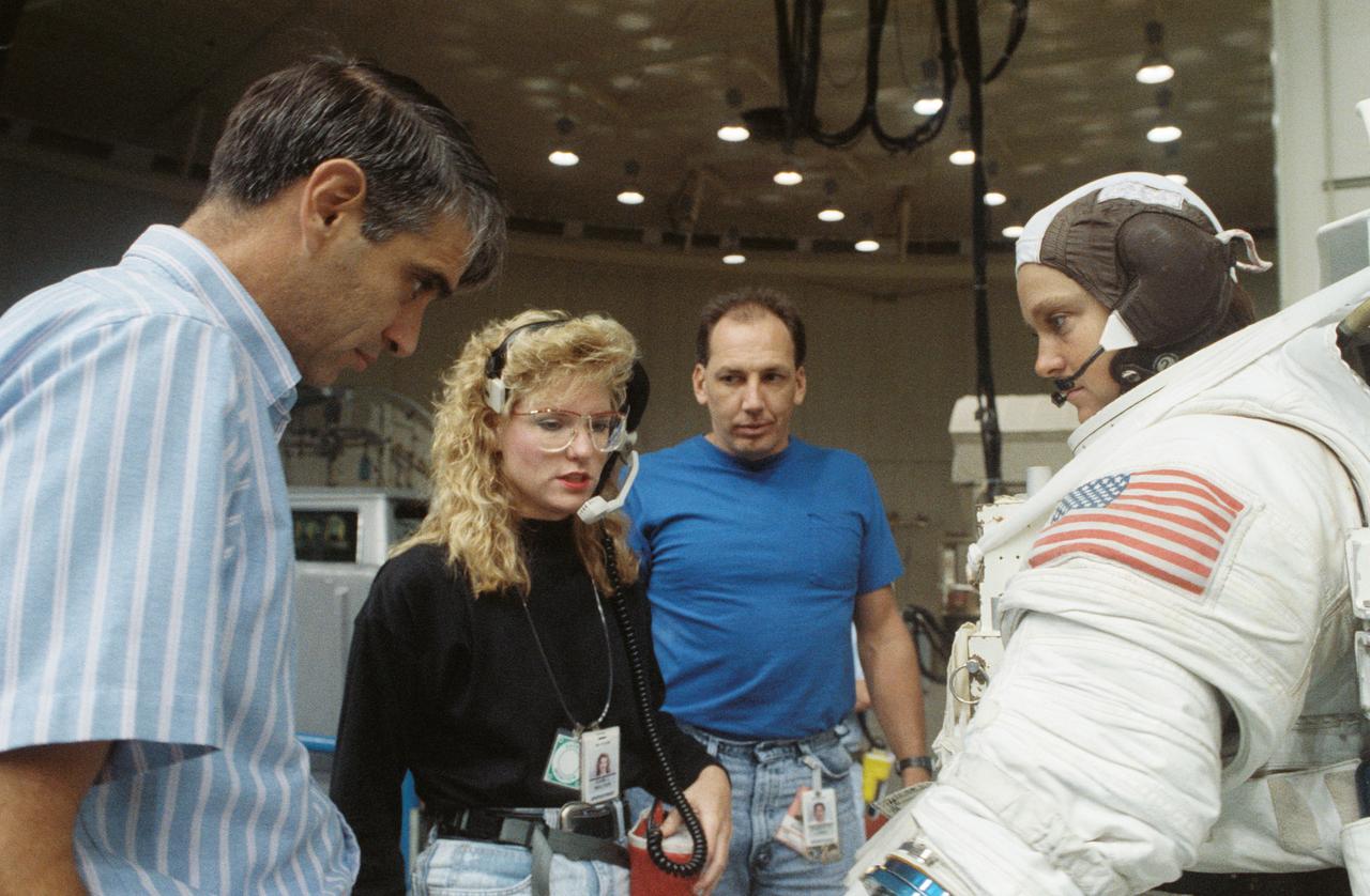 S90-45785 (16 Aug 1990) --- Astronaut Tamara E. Jernigan, STS-40 mission specialist, is pictured in a training version of the extravehicular mobility unit (EMU) spacesuit talking with a fellow crewmember and members of the crew training staff.  At left is astronaut Sidney M. Gutierrez, pilot for the flight.  Dr. Jernigan was about to be submerged in the Johnson Space Center's 25-ft. deep weightless environment training facility (WET-F) pool to simulate a contingency extravehicular activity (EVA).  There is no EVA scheduled for STS-40, the Spacelab Life Sciences (SLS-1) mission.
