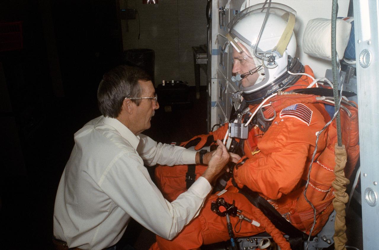 S90-47148  (21 Aug 1990) --- Astronaut Thomas D. Akers, STS-41mission specialist, is assisted by Troy M. Stewart of the Shuttle support branch in NASA's Crew and Thermal Systems Division. The astronaut was about to join his four crewmates in participating in a simulation of their scheduled flight in JSC's fixed-base Shuttle mission simulator (SMS).