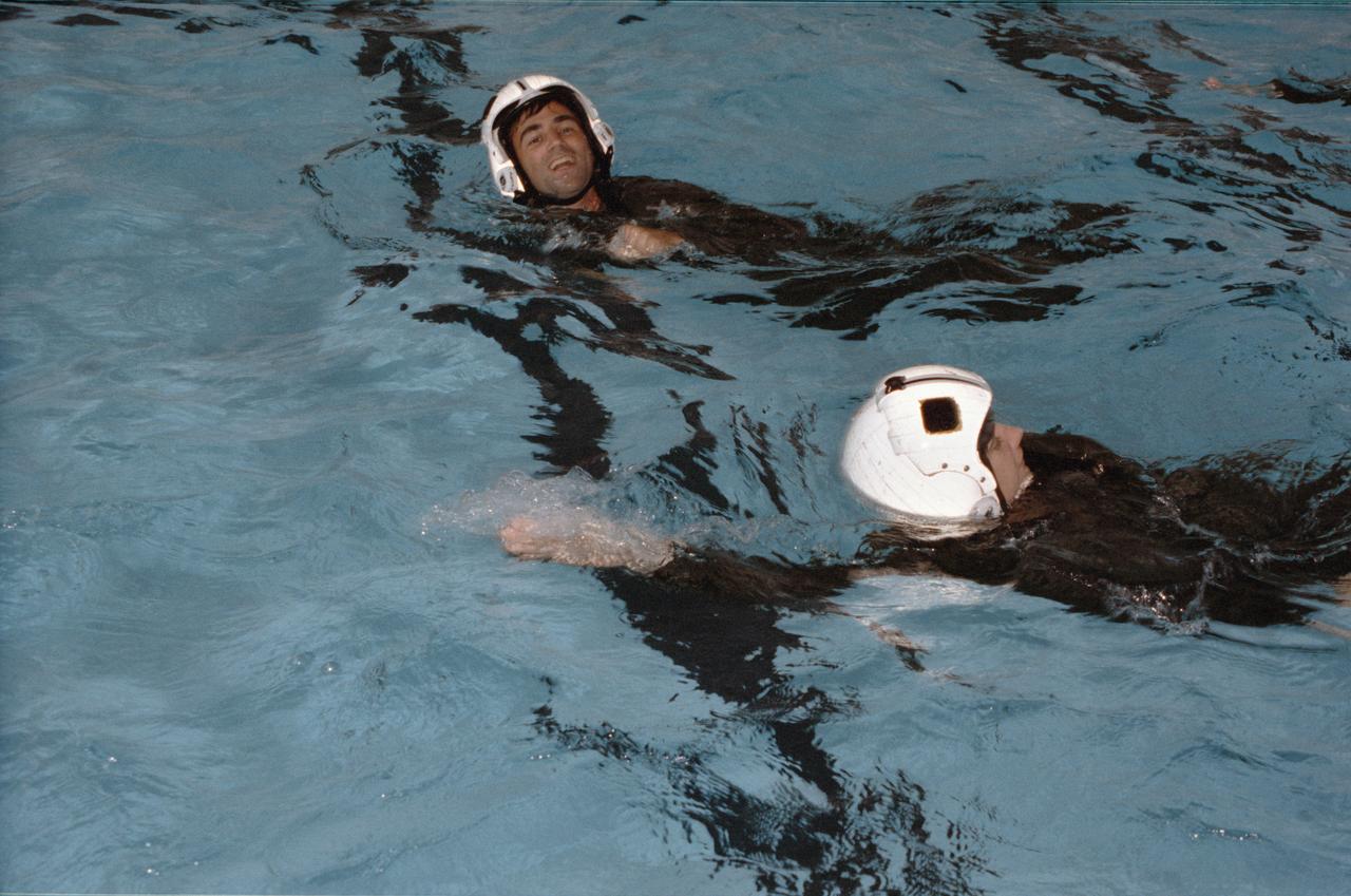 1990 Group 13 Astronaut Candidates (ASCANs) Susan J. Helms (foreground) and William G. Gregory, wearing helmets and flight suits, swim in pool at Elgin Air Force Base (AFB) in Pensacola, Florida, during water survival exercises. The training familiarized the candidates with survival techniques necessary in the event of a water landing. ASCANs participated in the exercises from 08-14-90 through 08-17-90.