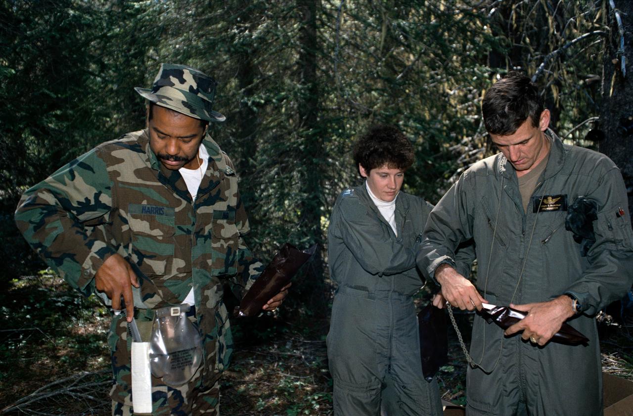 1990 Group 13 Astronaut Candidates (ASCANs) (left to right) Bernard J. Harris, Jr, Susan J. Helms, and William S. McArthur, Jr open dehydrated food packages during wilderness survival training at Fairchild Air Force Base (AFB) in Spokane, Washington. The training was conducted in the mountain forests of Washington from 08-26-90 through 08-30-90.