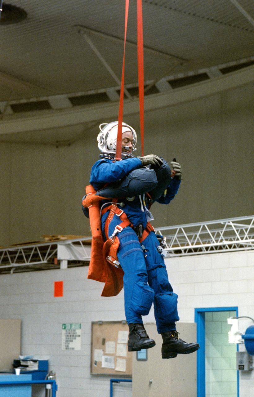 S90-54755 (13 Dec 1990) --- Astronaut Guion S. Bluford, Jr., STS-39 Mission Specialist wearing launch and entry suit (LES) and launch and entry helmet (LEH), is suspended above JSC's Weightless Environment Training Facility (WETF) Bldg 29 pool via his parachute harness. Bluford will be dropped from the harness into the WETF's 25 ft deep pool to simulate an emergency egress bailout from the Space Shuttle into the ocean.