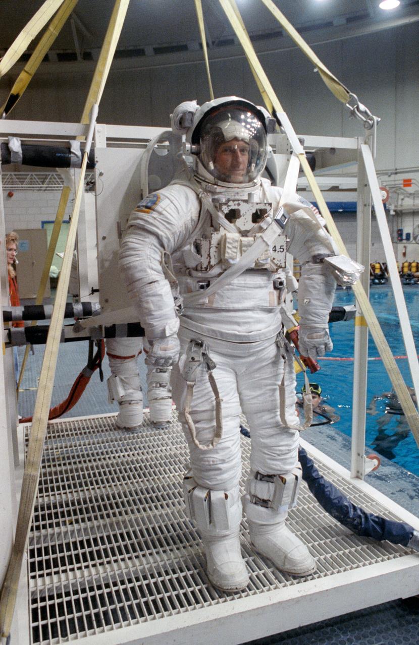 S91-30196 (1 March 1991) --- Astronaut C. Michael Foale, mission specialist, and Kathryn D. Sullivan, payload commander (barely visible in background), stand on a platform (out of frame) which is part of a system that will lower them into a 25-ft. deep pool.  The payload commander and mission specialist used the pool in the weightless environment training facility (WET-F) to rehearse a contingency extravehicular activity (EVA).  Astronauts wear pressurized spacesuits configured for achieving a neutrally buoyant condition in the water to simulate both planned and contingency EVAs.  Two SCUBA-equipped swimmers assisting the training are seen in the background.