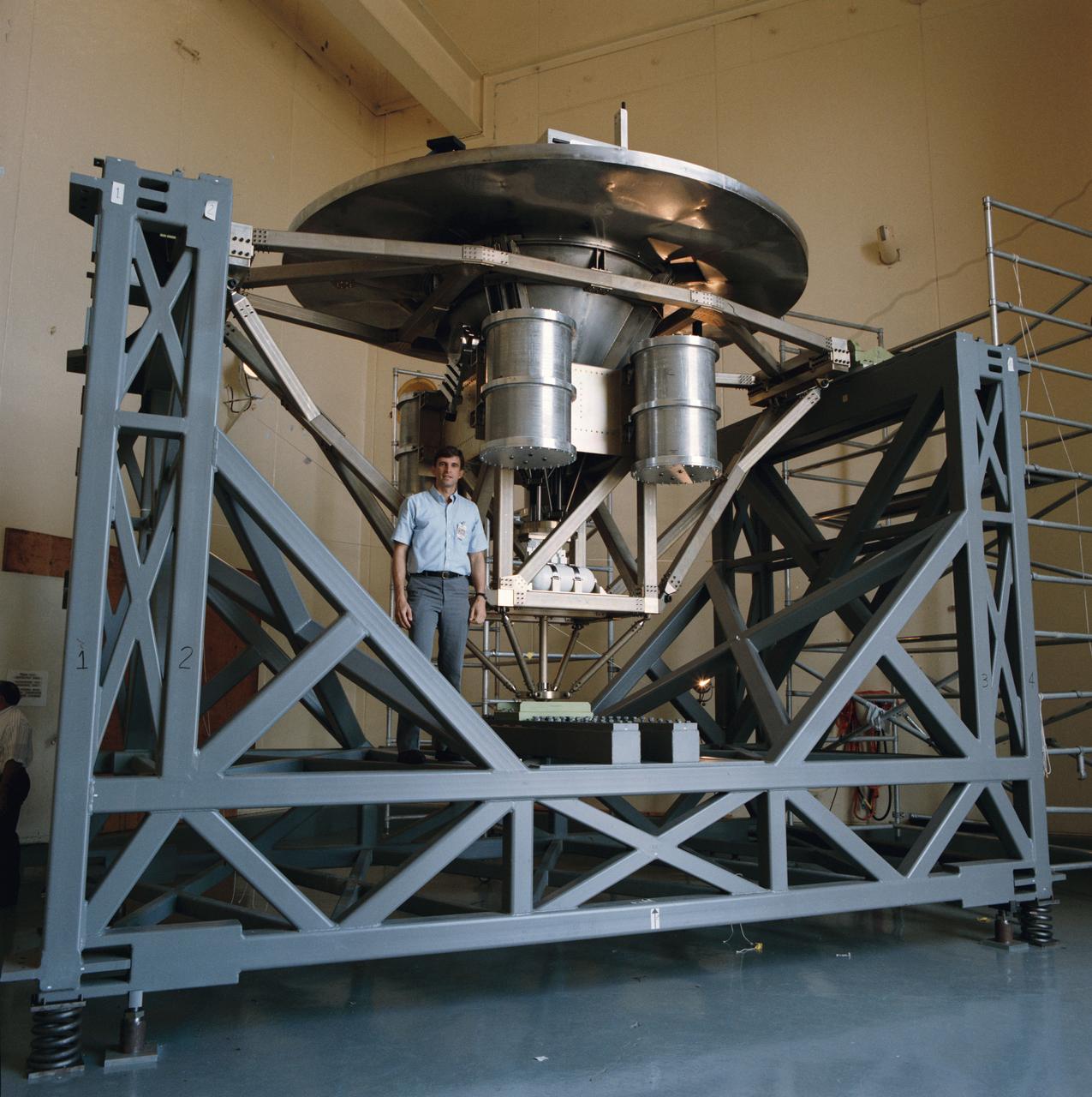 Astronaut Ronald M. Sega stands beside the University of Houston's Wake Shield Facility before it undergoes a Modal Survey Test in the Vibration and Acoustic Test Facility Building 49, prior to being flown on space shuttle mission STS-60.