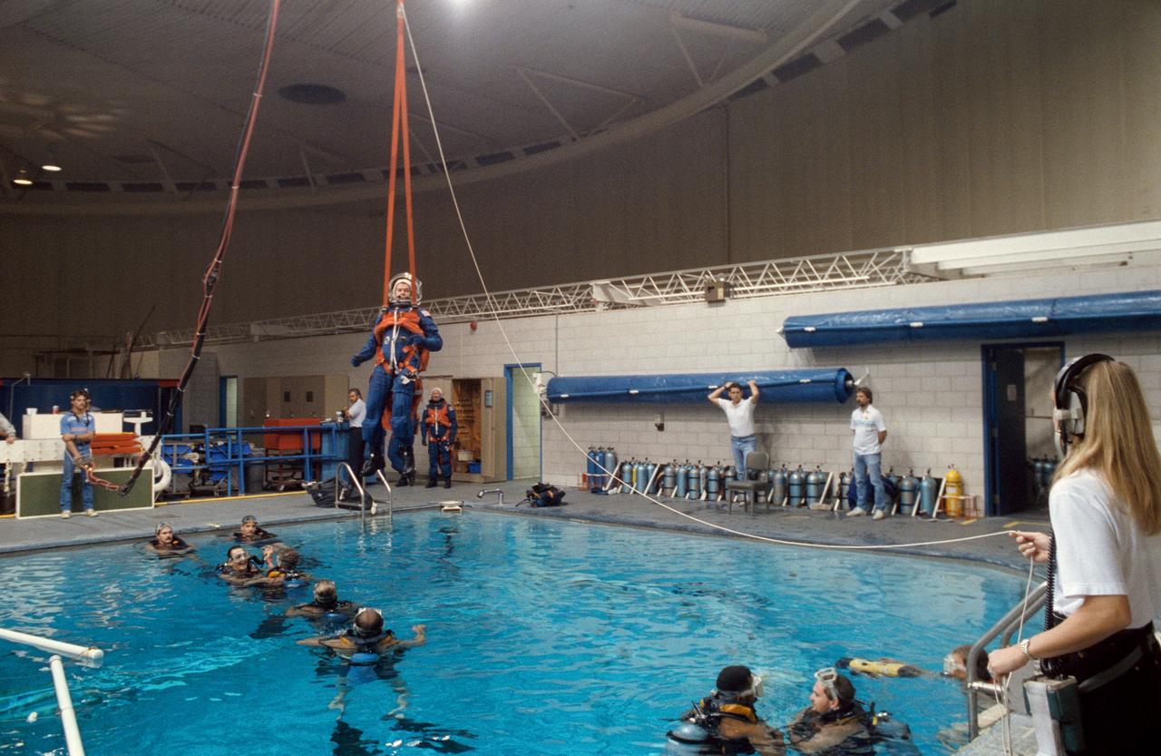 S91-52074 (26 Nov 1991) --- Charles R. (Rick) Chappell, alternate payload specialist, equipped with simulated parachute gear, descends into the water during bail-out training exercises in the Johnson Space Center's weightless environment training facility (WET-F). In this phase of the training program, Shuttle crewmembers learn the proper measures to take in the event of ejection and subsequent parachute landing into a body of water. A number of SCUBA-equipped swimmers who assisted in the training are pictured.