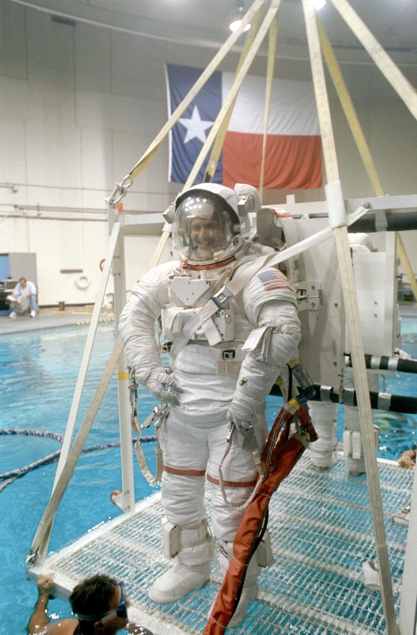 S92-40378 (1 July 1992) --- Astronaut Peter J.K. Wisoff, STS-57 mission specialist, fully suited in an extravehicular mobility unit (EMU) and helmet and standing on a platform, is lowered into the 25 foot deep pool of Johnson Space Center?s (JSC) Weightless Environment Training Facility (WETF) Bldg 29. Once underwater, Wisoff will participate in an underwater extravehicular activity (EVA) simulation. A scuba-equipped diver already in the pool guides the platform into the water.