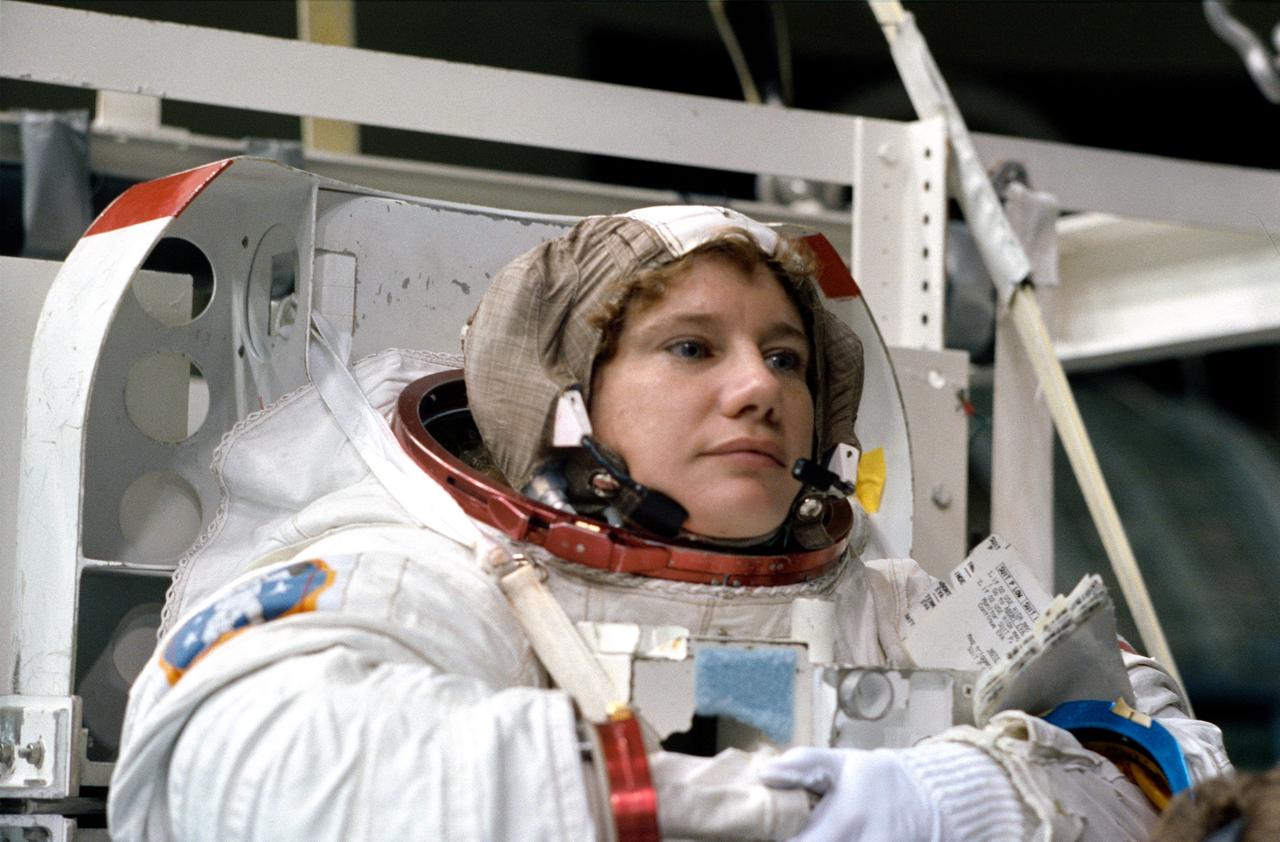 S92-42755 (31 July 1992) --- Astronaut Susan J. Helms, mission specialist assigned to fly aboard the Space Shuttle Endeavour for the STS-54 mission, completes the donning of her spacesuit before a training exercise. Though not assigned to the scheduled extravehicular activity (EVA), Helms is trained in the weightless environment training facility (WET-F). She will aid astronauts Gregory J. Harbaugh and Mario Runco Jr. in their planned EVA, scheduled for January of next year, and serve a backup role. Wearing this high fidelity training version of the extravehicular mobility unit (EMU), Helms was later lowered into the 25-ft. deep WET-F pool. The pressurized suit is weighted so as to allow Helms to achieve neutral buoyancy and simulate the various chores of the spacewalk.