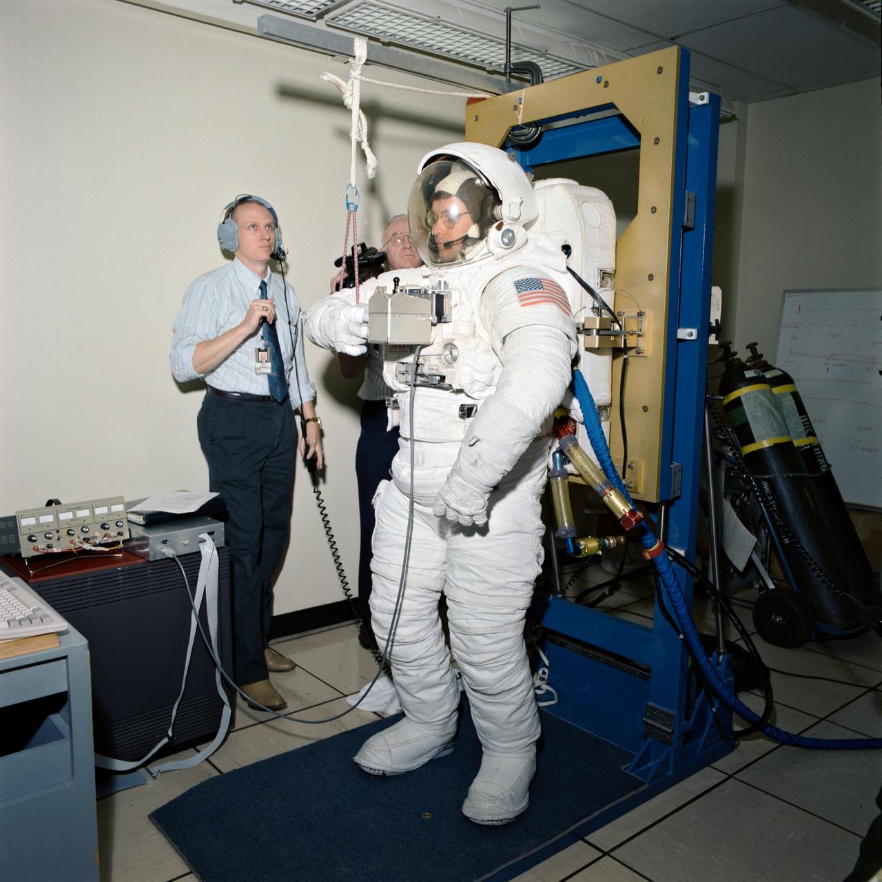 S93-26918 (8 Sept. 1994) --- Scott Bleisath, an extravehicular activity (EVA) engineer, demonstrates the hand control module for the Simplified Aid for EVA Rescue (SAFER) system making its first flight on the scheduled September STS-64 mission. Astronauts Mark C. Lee and Carl J. Meade are the spacewalkers assigned to test the system in space.  Unidentified technicians and engineers look on. Photo credit: NASA or National Aeronautics and Space Administration