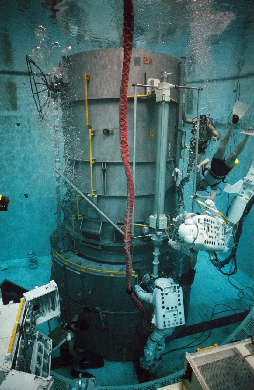 S93-30237 (5 Mar 1993) --- Wearing training versions of Space Shuttle Extravehicular Mobility Units (EMU), astronauts Thomas D. Akers (red stripe) and Kathryn C. Thornton use the spacious pool of the Johnson Space Center's (JSC) Weightless Environment Training Facility (WET-F) to rehearse for the Hubble Space Telescope (HST) servicing mission. They are working with part of a full-scale mockup of HST.