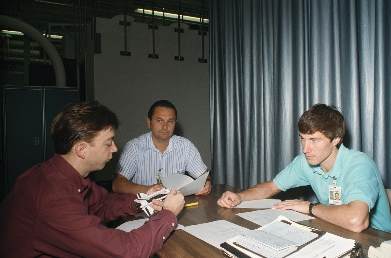 STS-60 Discovery, Orbiter Vehicle (OV) 103, Russian Mission Specialist Sergei Krikalev and Russian backup Mission Specialist Vladimir Titov work with Training Instructor Richard M. Davis (holding space shuttle model) prior to entering the Building 16 Systems Engineering Simulator (SES).