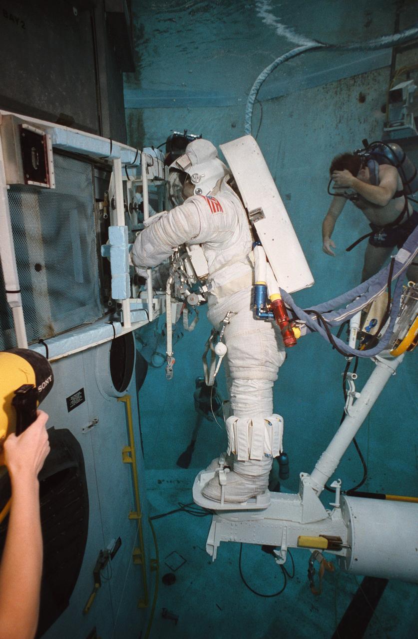 S93-33101 (5 Apr 1993) --- Wearing a training version of Space Shuttle Extravehicular Mobility Unit (EMU), astronaut Kathryn C. Thornton uses the giant pool of the Johnson Space Center's (JSC) Weightless Environment Training Facility (WET-F) to rehearse for the Hubble Space Telescope (HST) repair mission.  Standing on a mobile foot restraint connected to the Shuttle's robot arm, Thornton grasps a large structure which attaches to the Wide Field/Planetary Camera (WF/PC).  The current WF/PC on the HST will be replaced with WF/PC-2.  Out of frame is astronaut Thomas D. Akers, who will join Thornton in STS-61 EVA.  A SCUBA-equipped diver can be seen in the background.  A number of divers are on hand for all training sessions in the WET-F.  A total of five extravehicular activity (EVA) sessions will be conducted during the scheduled December mission of the Endeavour.