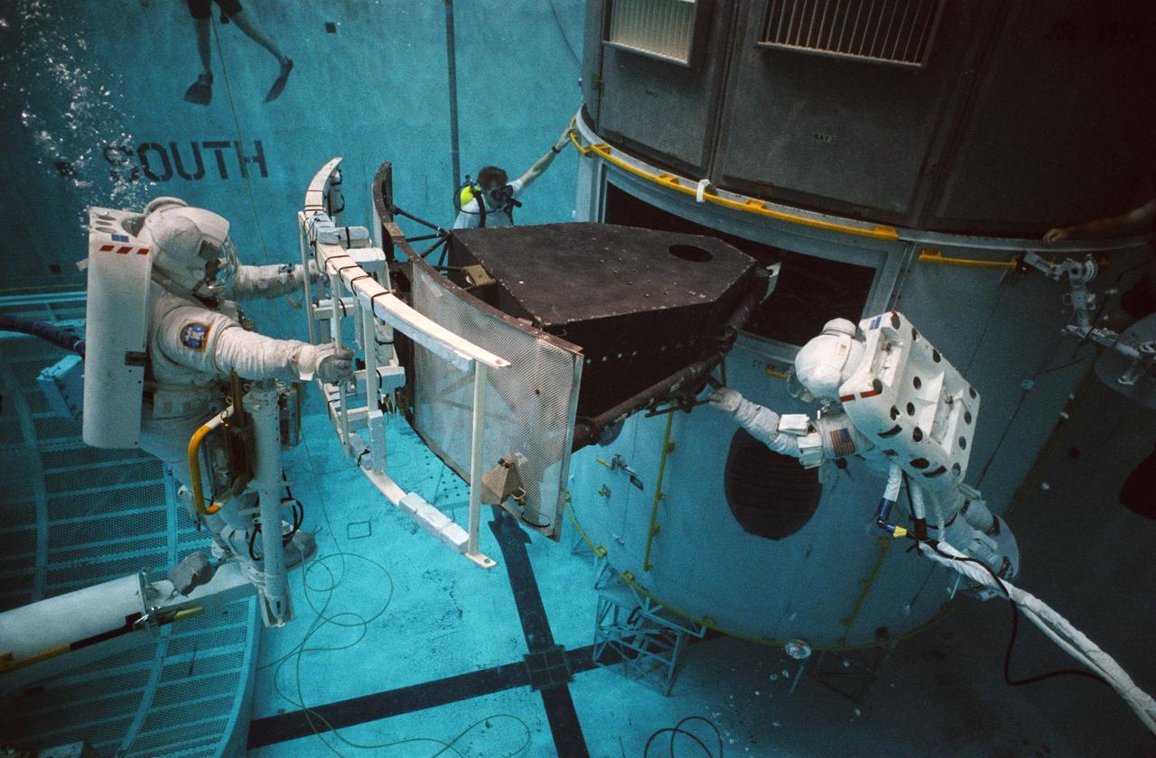 S93-33103 (2 Apr 1993) --- Wearing training versions of Space Shuttle Extravehicular Mobility Units (EMU), astronauts F. Story Musgrave and Jeffrey A. Hoffman use the giant pool of the Johnson Space Center's (JSC) Weightless Environment Training Facility (WET-F) to rehearse for the Hubble Space Telescope (HST) repair mission.  The two are working with a full-scale training version of the Wide Field/Planetary Camera (WF/PC).  The current WF/PC will be replaced with WF/PC-2.  A total of five extravehicular activity (EVA) sessions will be conducted during the scheduled December mission of the Endeavour.