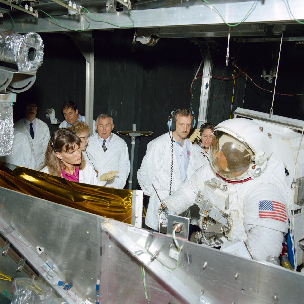 S93-34001 (26 May 1993) --- Astronaut F. Story Musgrave, wearing a training version of the Extravehicular Mobility Unit (EMU), participates in a dry run for tests in a thermal vacuum chamber.  The payload commander will be among four suited crew members participating in task rehearsals and testing the tools that will be used on the Hubble Space Telescope (HST) repair mission.  The test, conducted in Chamber B of the Space Environment and Simulation Laboratory (SESL) at the Johnson Space Center (JSC), verified that the tools being designed for the mission will work in the cold vacuum of space.  Others pictured, from the left, are Andrea Tullar and Donna Fender, test directors; Leonard S. Nicholson, acting director of engineering; and astronauts Thomas D. Akers and Kathryn C. Thornton, mission specialists, along with Musgrave.
