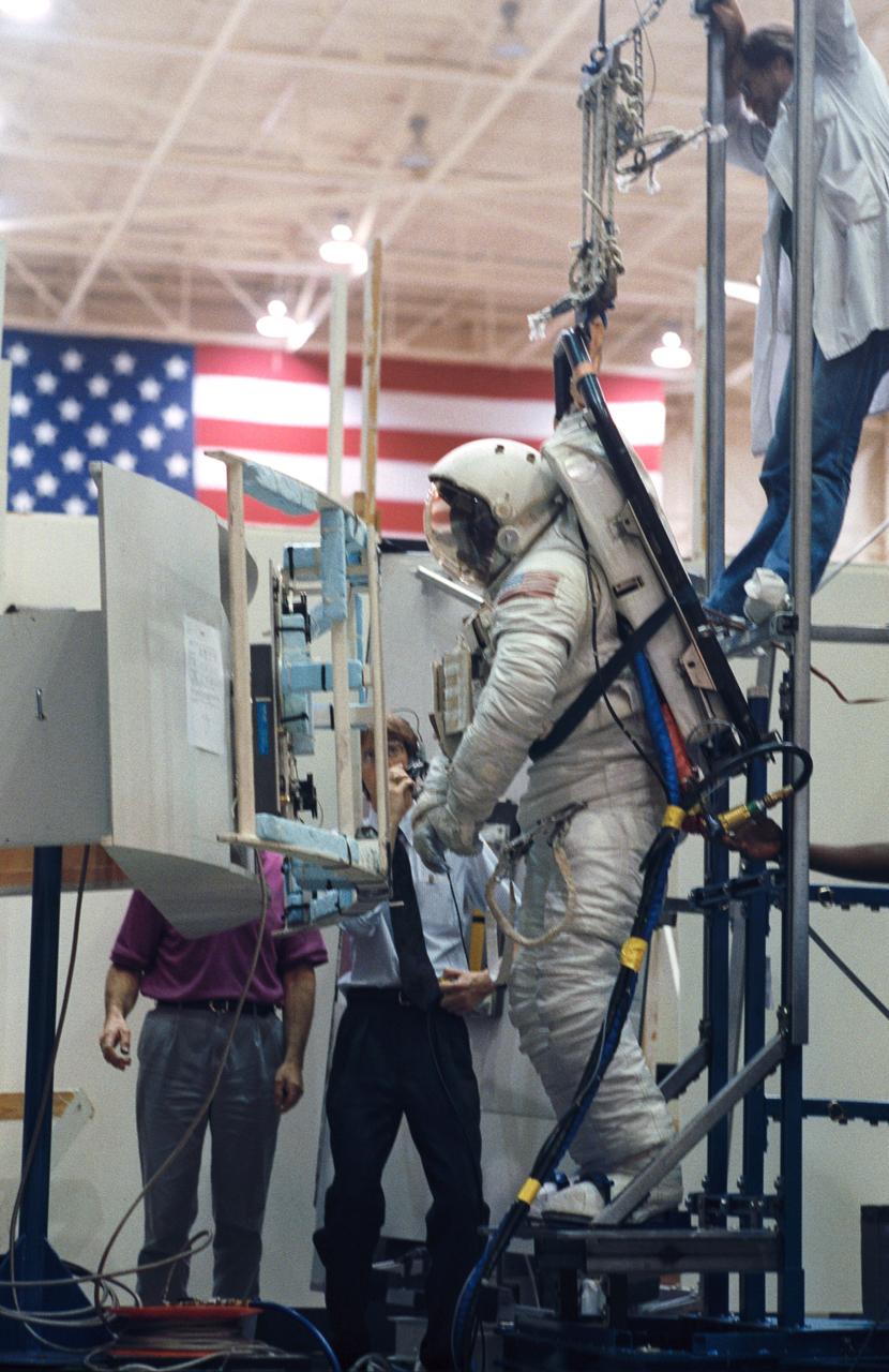 Making use of the air-bearing floor in JSC's Shuttle mockup and integration laboratory, Astronaut Jeffrey A. Hoffman practices working with the Hubble Space Telescope's Wide Field/Planetary Camera (WF/PC). Changing out the large camera is one of several jobs to be performed by STS-61.