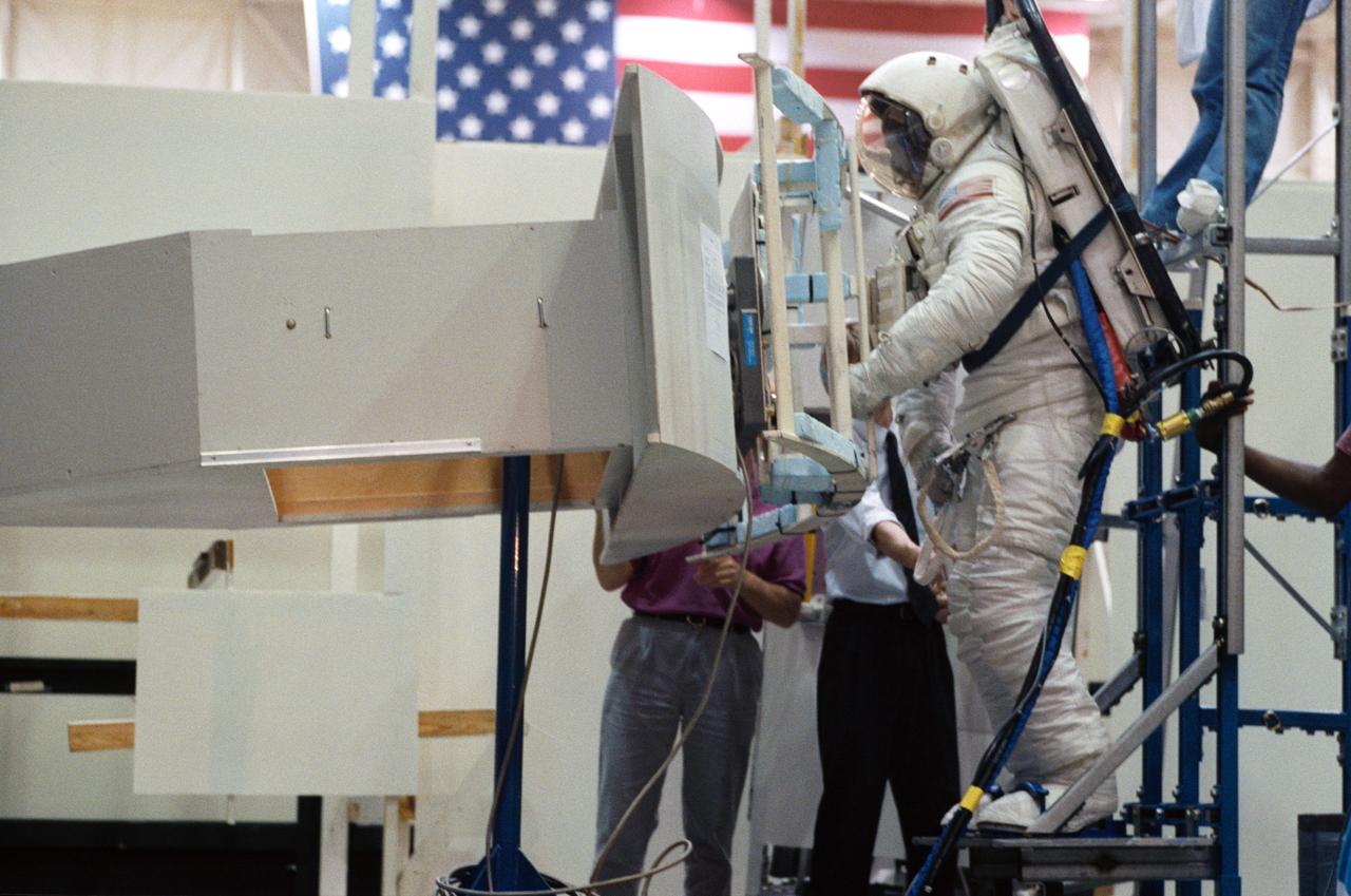Making use of the air-bearing floor in JSC's Shuttle mockup and integration laboratory, Astronaut Jeffrey A. Hoffman practices working with the Hubble Space Telescope's Wide Field/Planetary Camera (WF/PC). Changing out the large camera is one of several jobs to be performed by STS-61.
