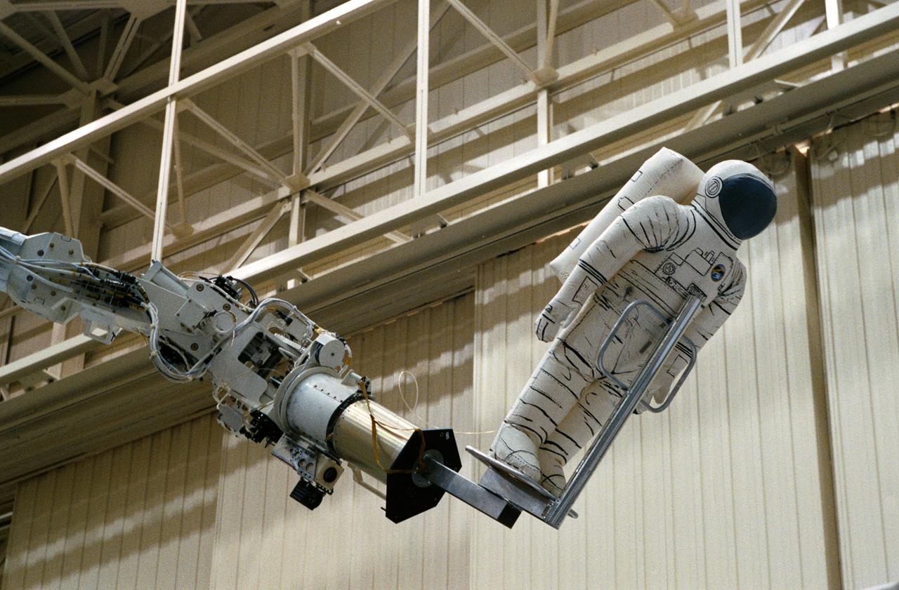 The Remote Manipulator System (RMS) eases a mannequin representing an astronaut into position for an STS-61 Hubble Space Telescope (HST) servicing task in the Space Shuttle mockup and integration laboratory at JSC (35699, 35703); Wide-angle view of the RMS easing a mannequin into position for work on the HST mock-up in bldg 9N (35700-1); Swiss scientist Claude Nicollier, mission specialist, works the control of the RMS during a training session in the manipulator development facility (MDF) in JSC's Shuttle mock-up and integration laboratory. Astronaut Kenneth D. Bowersox (left), pilot, is among the other crewmembers in training for the STS-61 HST servicing mission (35702).