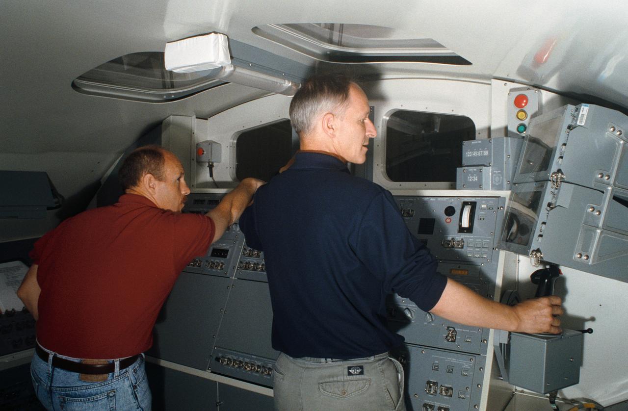 The Remote Manipulator System (RMS) eases a mannequin representing an astronaut into position for an STS-61 Hubble Space Telescope (HST) servicing task in the Space Shuttle mockup and integration laboratory at JSC (35699, 35703); Wide-angle view of the RMS easing a mannequin into position for work on the HST mock-up in bldg 9N (35700-1); Swiss scientist Claude Nicollier, mission specialist, works the control of the RMS during a training session in the manipulator development facility (MDF) in JSC's Shuttle mock-up and integration laboratory. Astronaut Kenneth D. Bowersox (left), pilot, is among the other crewmembers in training for the STS-61 HST servicing mission (35702).