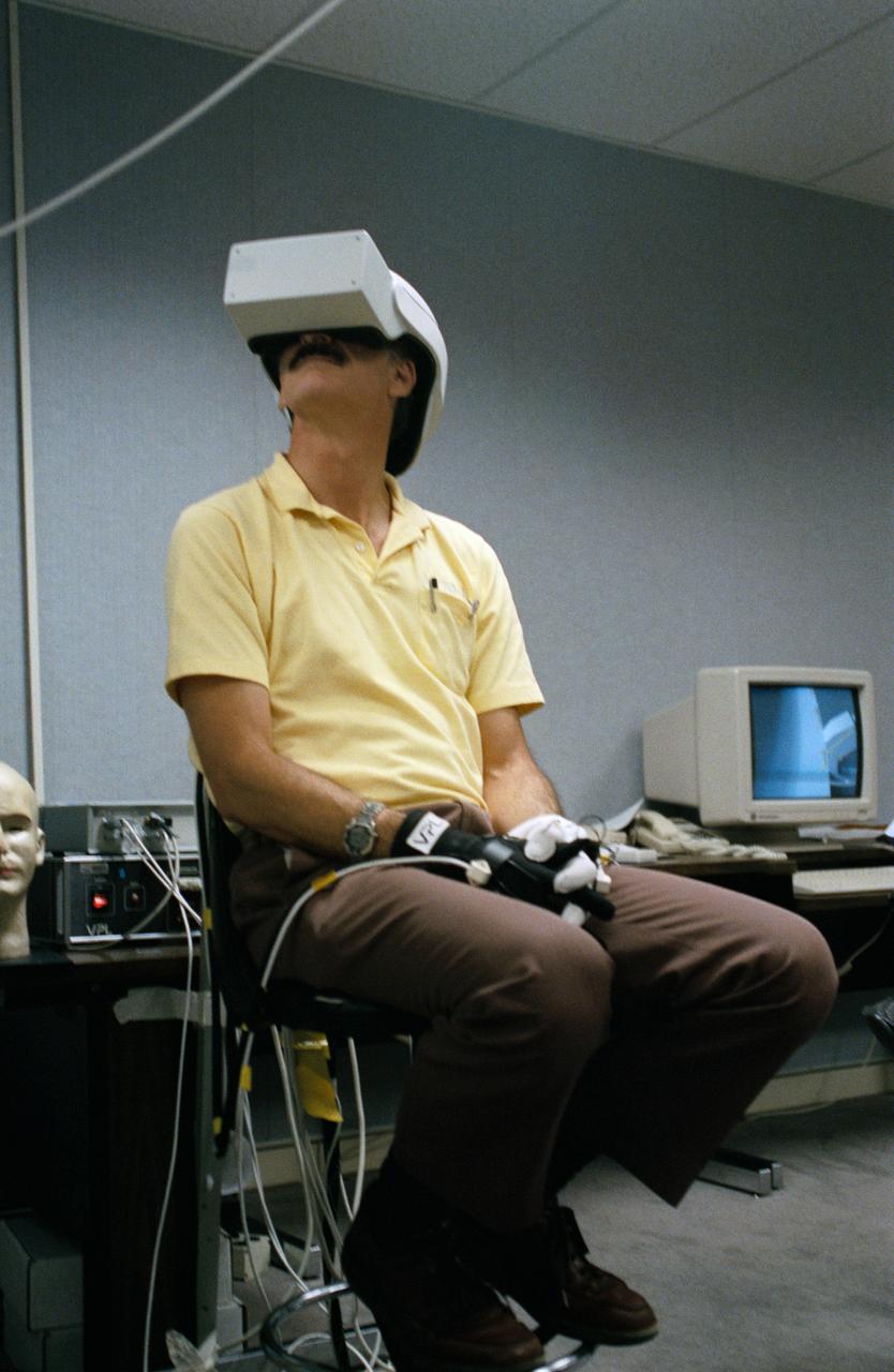 Astronaut Jeffrey A. Hoffman, one of four crewmembers for STS-61 that will conduct scheduled spacewalks during the flight, wears a special helmet and gloves designed to assist in proper positioning near the telescope while on the end of the robot arm. Crewmembers are utilizing a new virtual reality training aid which assists in refining positioning patterns for Space Shuttle Endeavour's Remote Manipulator System (RMS) (36890); Astronaut Claude Nicollier looks at a computer display of the Shuttle's robot arm movements as Thomas D. Akers and Kathryn C. Thornton, mission specialists look on. Nicollier will be responsible for maneuvering the astronauts while they stand in a foot restraint on the end of the RMS arm (36891,36894); Hoffman wears a special helmet and gloves designed to assist in proper positioning near the telescope while on the end of the robot arm (35892); Nicollier looks at a computer display of the Shuttle's robot arm movements as Akers looks on (36893); While (l-r) Astronauts Kenneth Bowersox, Kathryn Thornton, Richard O. Covey and Thomas D. Akers watch, Nicollier moves the Robot arm to desired locations in the Shuttle's payload bay using the Virtual Reality program (36895); Bowersox takes his turn maneuvering the RMS while mission specialist Hoffman, wearing the Virtual Reality helmet, follows his own progress on the end of the robot arm. Crewmembers participating during the training session are (l-r) Astronauts Akers, Hoffman, Bowersox, Nicollier, Covey, and Thornton. In the background, David Homan, an engineer in the JSC Engineering Directorate's Automation and Robotics Division, looks on (36896).
