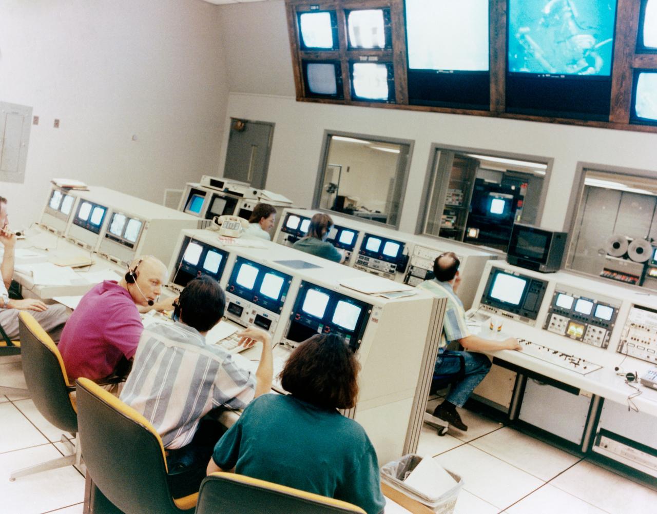 Astronauts Jeffrey A. Hoffman (far left) and F. Story Musgrave (second left) monitor a training session from consoles in the control room for the Neutral Buoyancy Simulator (NBS) at the Marshall Space Flight Center (MSFC). Seen underwater in the NBS on the big screen and the monitors at the consoles is astronaut Thomas D. Akers. The three mission specialists, along with astronaut Kathryn C. Thornton, are scheduled to be involved in a total of five sessions of extravehicular activity (EVA) to service the Hubble Space Telescope (HST) in orbit during the STS-61 mission, scheduled for December 1993.