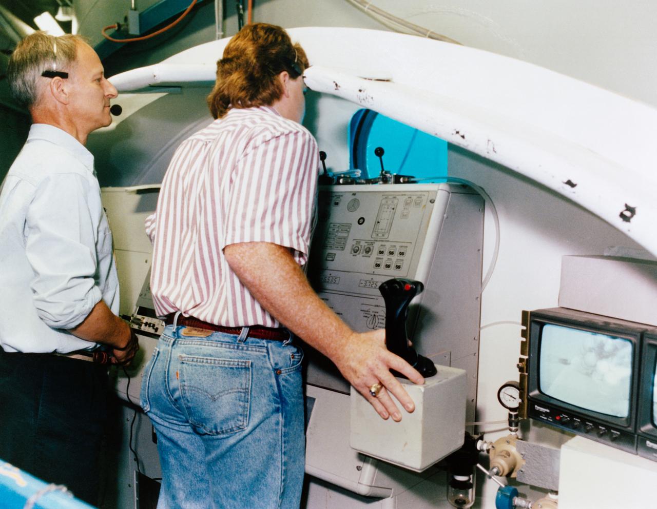 Swiss scientits Claude Nicollier (left), STS-61 mission specialist, waits his turn at the controls for the remote manipulator system (RMS) during a training session in the Neutral Buoyancy Simulator at Marshall Space Flight Center (MSFC). Mark Norman of MSFC has control of the RMS in this frame.