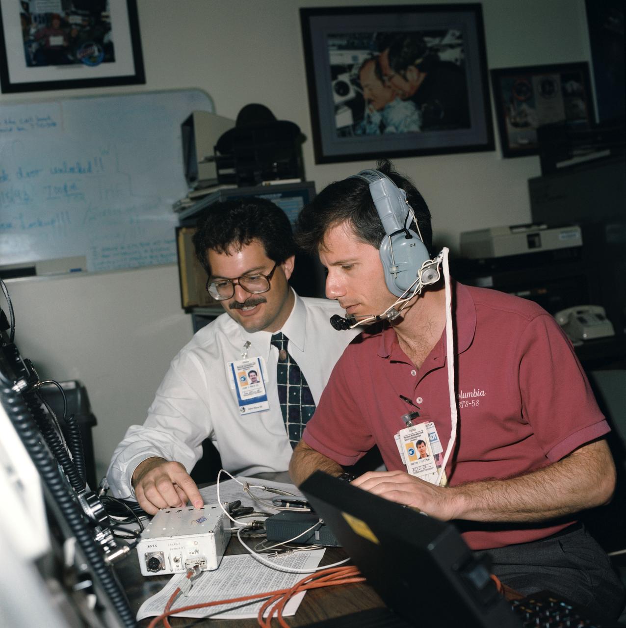 S93-45076 (22 Sept 1993) --- Payload specialist Martin J. Fettman listens to an amateur radio instruction by crew trainer John J. Maca.  Members of the STS-58 crew were training with amateur radio equipment at the Johnson Space Center (JSC).  The STS-58 flight will carry the Shuttle Amateur Radio Experiment (SAREX) payload, configuration C, which includes FM voice and packet.  Three of the seven crew members are licensed amateur radio operators.  Fettman's call letters are KC5AXA; William S. McArthur, mission specialist, KC5ACR; and Richard A. Searfoss, pilot, KC5CKM.  Licensed students at a number of schools around the country will have the opportunity to talk directly with the astronauts during the 14-day flight.